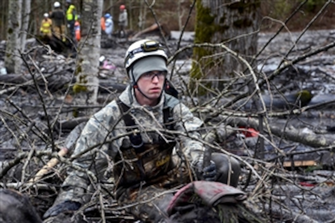 Air Force Staff Sgt. Jonathon Hernas carefully maneuvers across debris and mud while searching for survivors in Oso, Wash., March 28, 2014, following a deadly mudslide. Hernas is assigned to the Washington National Guard's 141st Civil Engineer Squadron.