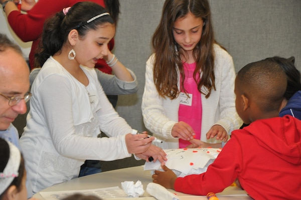 Children building a structure that can withstand the weight of a stack of books. Bring Your Child to Work Day - STEM Event