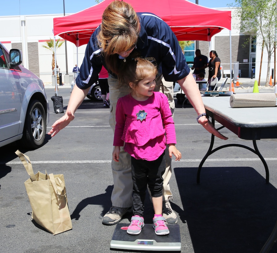 Melanie Weaver, police officer, California Highway Patrol, weighs Giavanna Escobar, 6, while explaining car seat weight limits during the Marine and Family Safety Fair at the Combat Center Exchange parking lot, April 28, 2014. “The National Highway Traffic Safety Administration estimates that approximately 80 percent of all car seats are used incorrectly,” Weaver said. “A lot of people don’t know, but car seats are like milk, meaning they expire.”