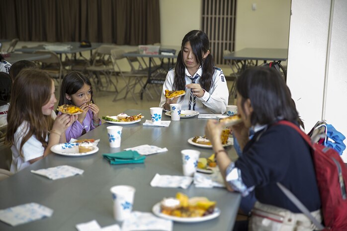 Japanese and American Girl Scouts eat pizza they made at the Marine Memorial Chapel aboard Marine Corps Air Station Iwakuni, Japan, April 25, 2014. The U.S. Girl Scouts invited their sister scouts to a cultural exchange to foster friendship and interact with one another. The girls divided into teams and had to decide how they wanted their pizza made.