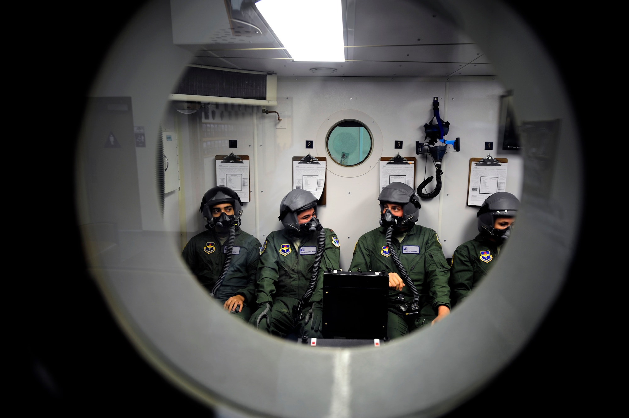 47th Student Squadron Class 15-09 student pilots await a seal check in the hypobaric chamber at the Aerospace Physiology Unit on Laughlin Air Force Base, Texas, April 30, 2014. Students are trained in a pressure-demand system where oxygen in the mask is above ambient pressure permitting breathing above 40,000 feet. Regulators furnish the mask with 100 percent oxygen under pressure to force the oxygen into the lungs, rather than depending on the low pressure produced when the wearer of the mask inhales to pull in the oxygen. (U.S. Air Force photo/Staff Sgt. Steven R. Doty/Released)