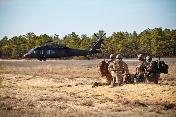 A picture of U.S. Air Force tactical air control party airmen from the 227th Air Support Operations Squadron standing by for transportation as a command a control UH-60 Black Hawk helicopter stands by.