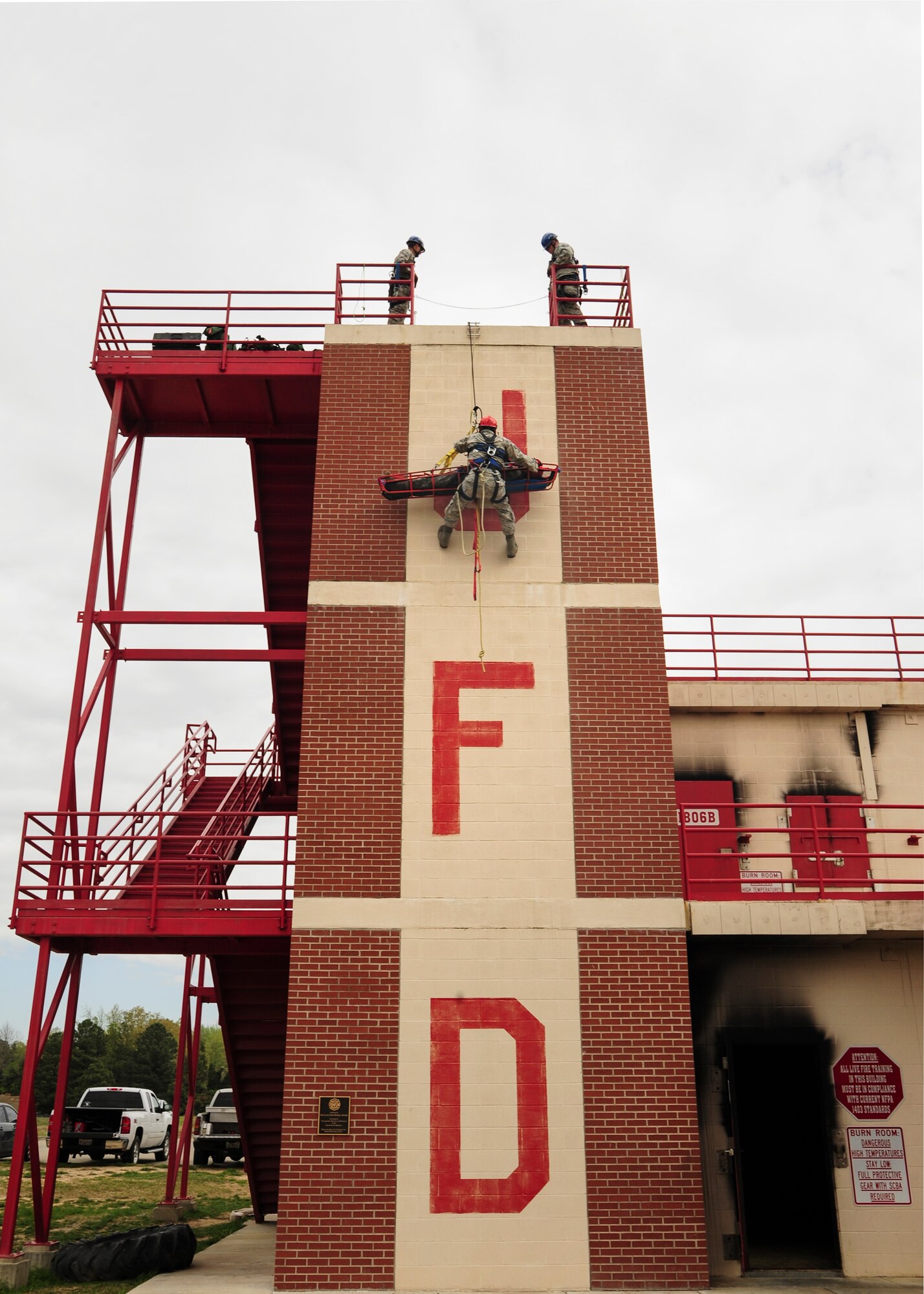An Airman from the 19th Airlift Wing civil engineer fire department repels down a wall with a simulated victim April 18, 2014, Jacksonville, Ark. The Jacksonville Fire Department allows Airmen from base to use their training building to practice a multitude of life-saving exercises.  (U.S. Air Force photo by Airman 1st Class Harry Brexel)