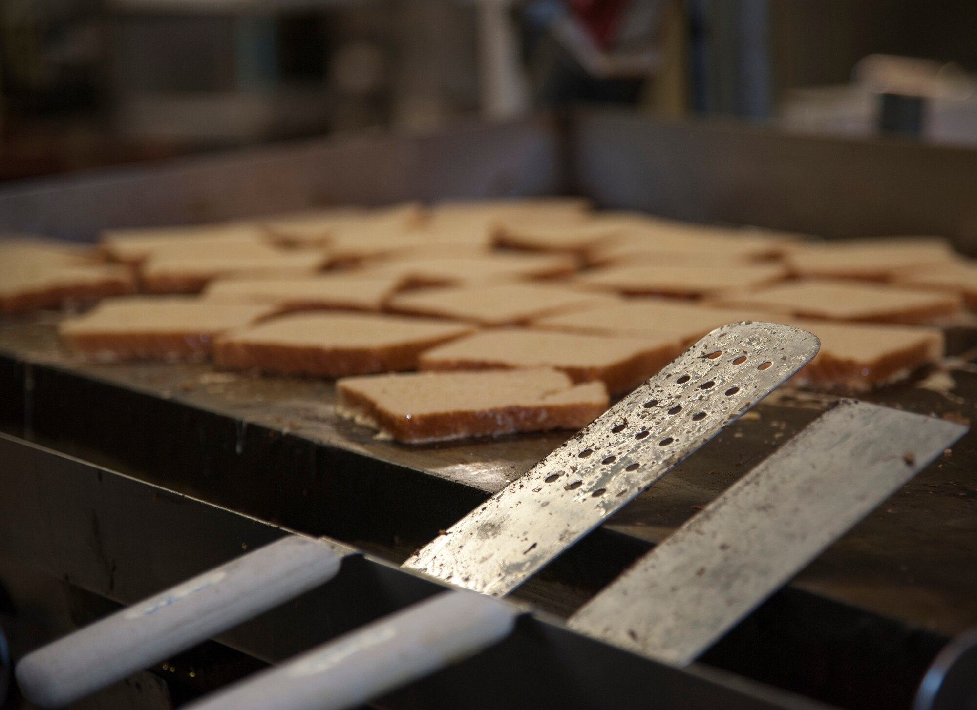 French toast warms up atop a grill in the kitchen of Club XL for pilot training class 14-08’s graduation breakfast on Laughlin Air Force Base, Texas, April 24, 2014. Club XL chefs prepare on average four loafs of bread for the graduating pilots and their families for graduation breakfast. (U.S. Air Force photo/Airman 1st Class Jimmie D. Pike/Released)  