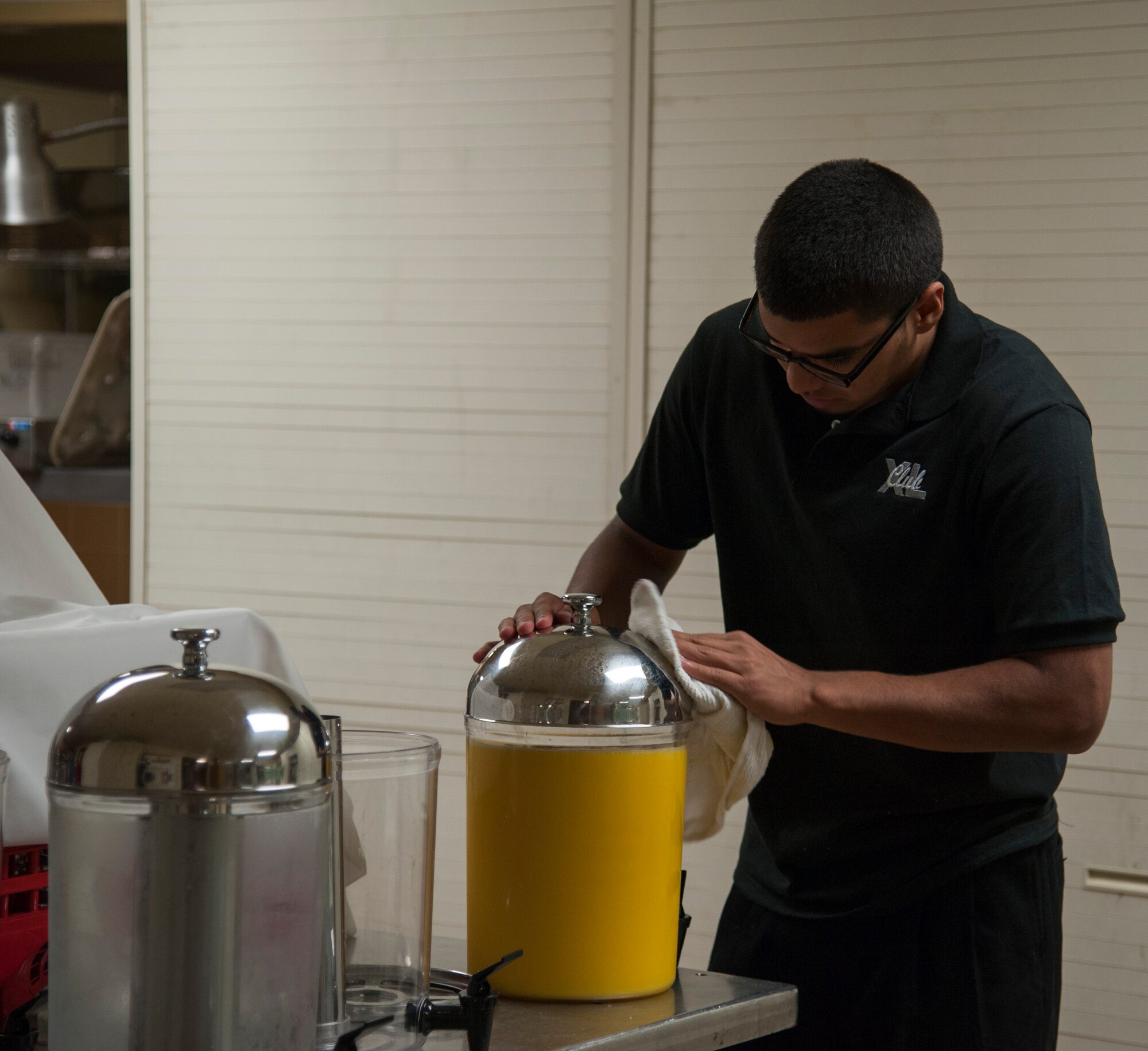 Eduardo Moreno, Club XL wait staff member, polishes an orange juice dispenser for pilot training class 14-08’s graduation breakfast at Club XL on Laughlin Air Force Base, Texas, April 24, 2014. The club prepares approximately four gallons of orange juice, coffee and more to meet the needs of its guests at graduation breakfast. (U.S. Air Force photo/Airman 1st Class Jimmie D. Pike/Released)  