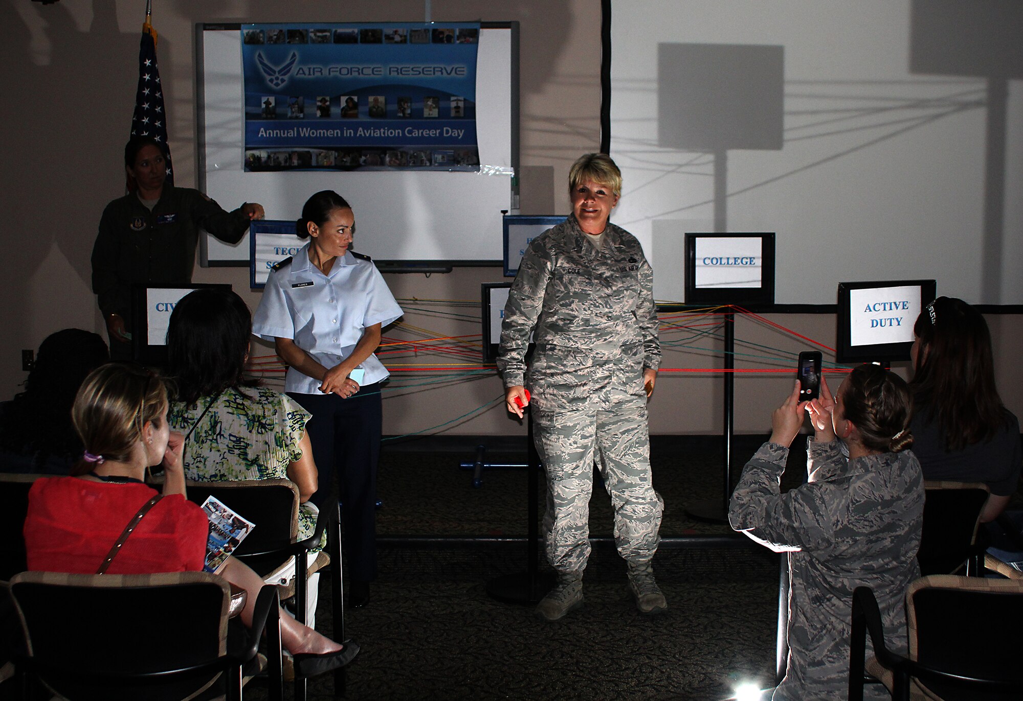 Chief Master Sgt. Deborah Cole, 38th Aerialport Squadron, and 2nd Lt. Kierstin Flores, 315th Aircraft Maintenance Squadron, tell the girls about their career journeys, while other 315th AW members illuminate them with flashlights. An unexpected power outage didn't stop 315th Airlift Wing members from continuing the days opening session and introduction for the 2014 2014 Joint Base Charleston Women in Aviation Career Day. (U.S. Air Force Photo by Michael Dukes)