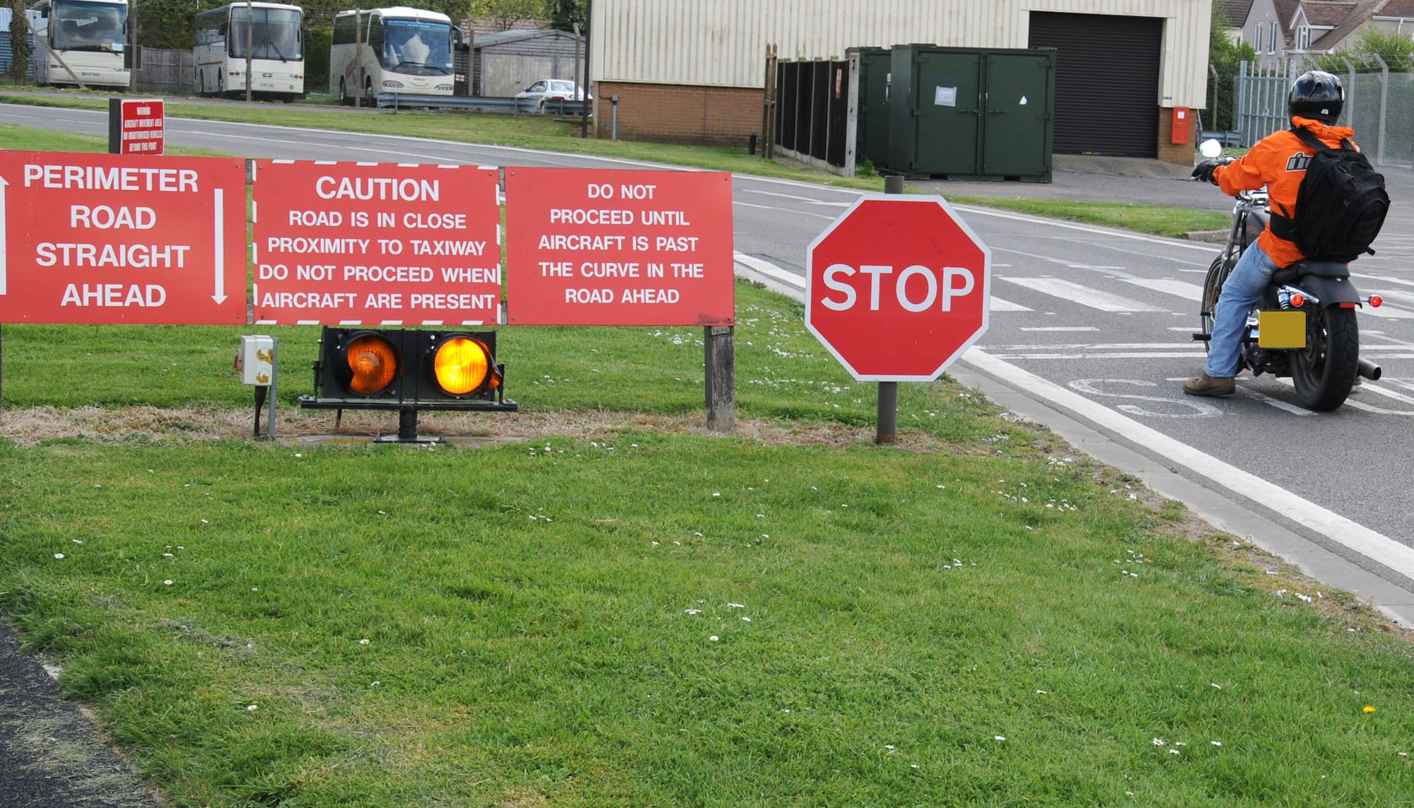 A Team Mildenhall motorcycle rider observes the warning signs and stops his motorcycle April 11, 2014, on RAF Mildenhall, England. It’s mandatory for all road users to follow posted instructions. Failing to stop could result in pilots having to emergency brake while taxiing to the runway, and motorcycles are harder to spot given their size and speed. (U.S. Air Force photo by Gina Randall/Released)