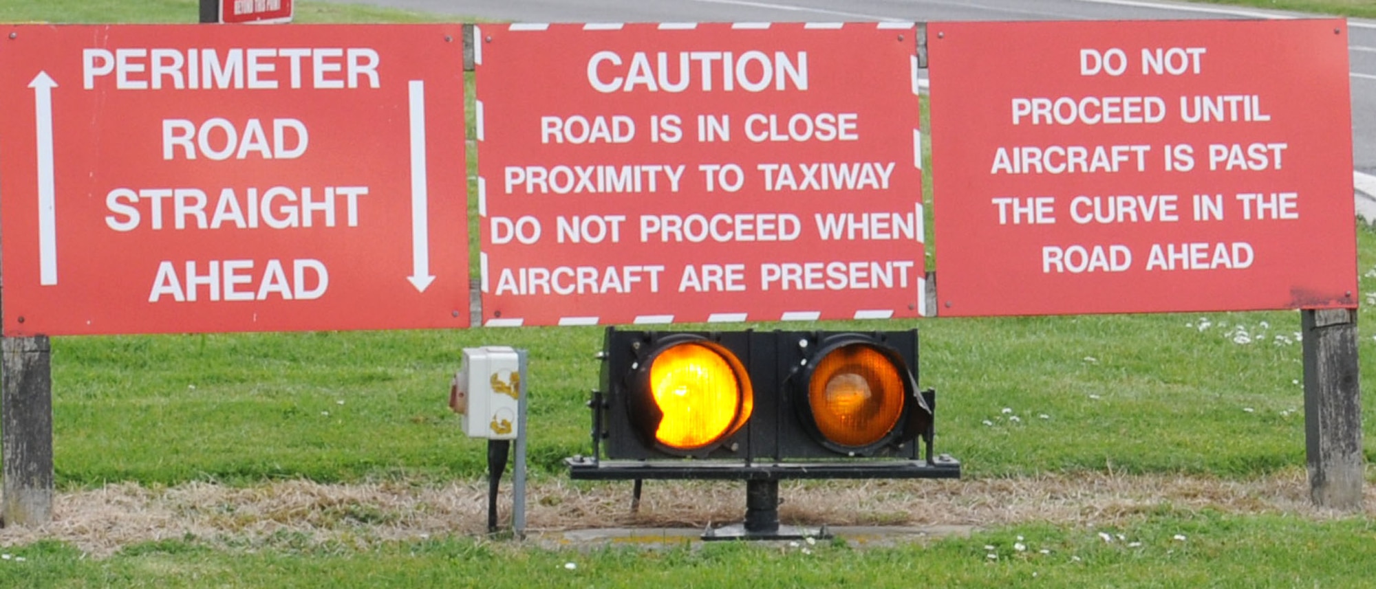 Road signs inform users to stop April 11, 2014, on Perimeter Road on RAF Mildenhall, England. The signs inform road users why they must stop and give way to aircraft. Flashing lights draw road users’ attention to the signs in low light conditions. (U.S. Air Force photo by Gina Randall/Released)