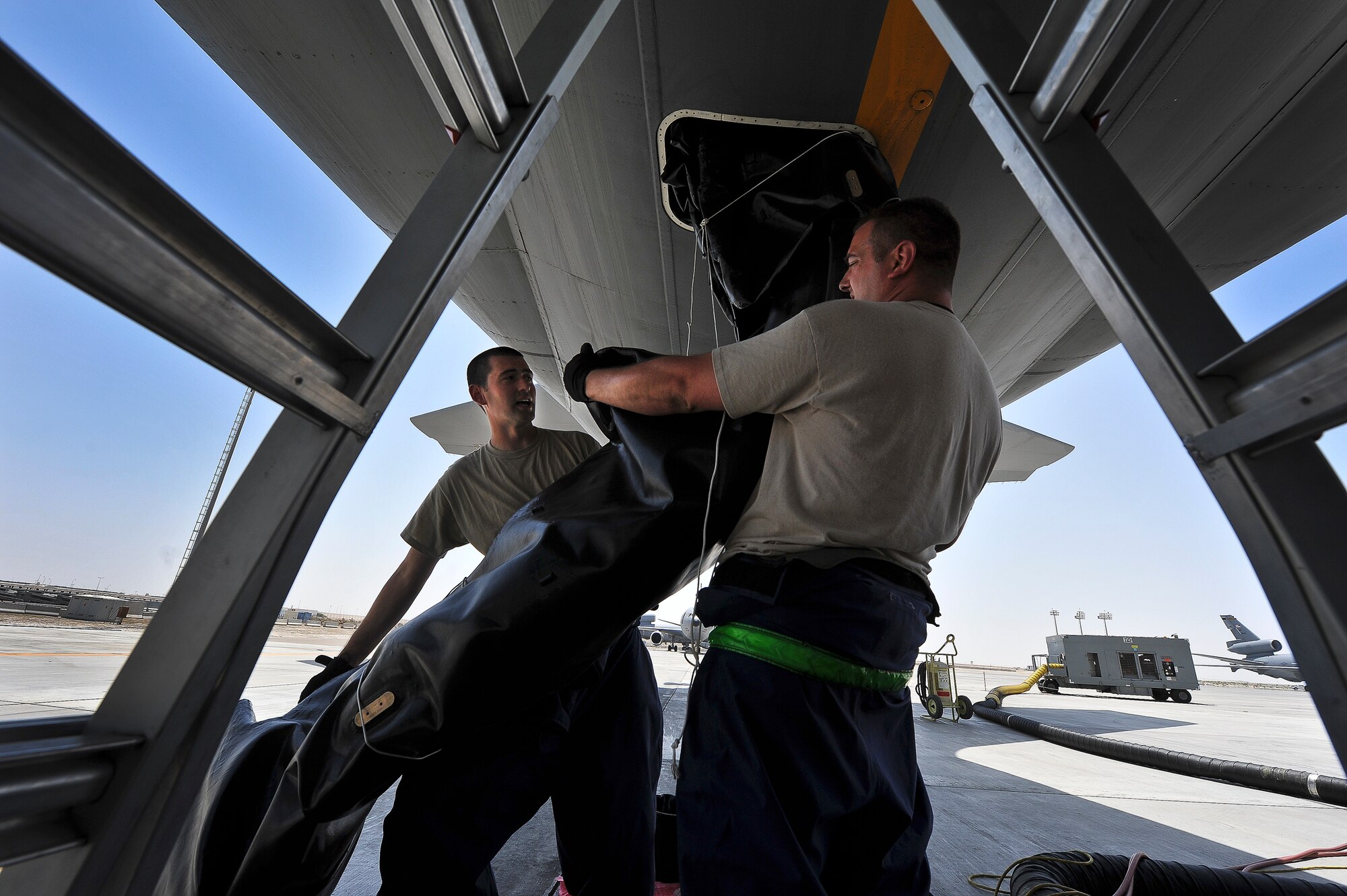 Airman 1st Class Eric Nulf (left), a 380th Expeditionary Aircraft Maintenance Squadron fuel systems journeyman and Staff Sgt. David Haack, a 380th Expeditionary Aircraft Maintenance Squadron fuel systems craftsman, lift a new bladder cell into a KC-10 Extender April 28, 2014, at an undisclosed location in Southwest Asia.  The team was replacing a cell that had ruptured. (U.S. Air Force photo byTech. Sgt. Russ Scalf/Released)