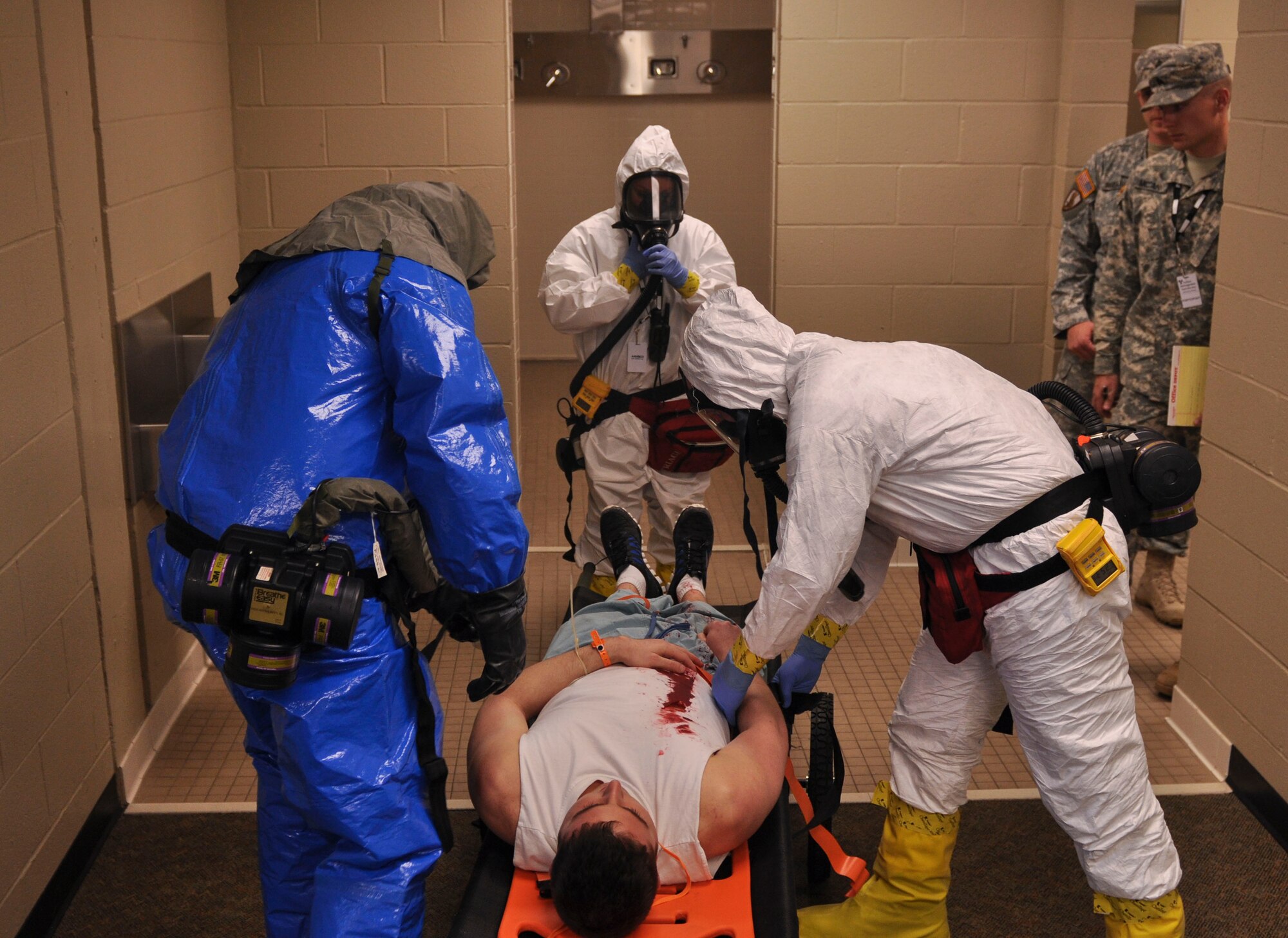 Participants of a field training exercise place a simulated injured Little Rock Air Force Base Airman on a backboard as inspectors observe April 22, 2014, at the University of Arkansas for Medical Sciences campus. More than 30 local, state and federal agencies participated in the two-day event. (U.S. Air Force photo by Senior Airman Regina Agoha)