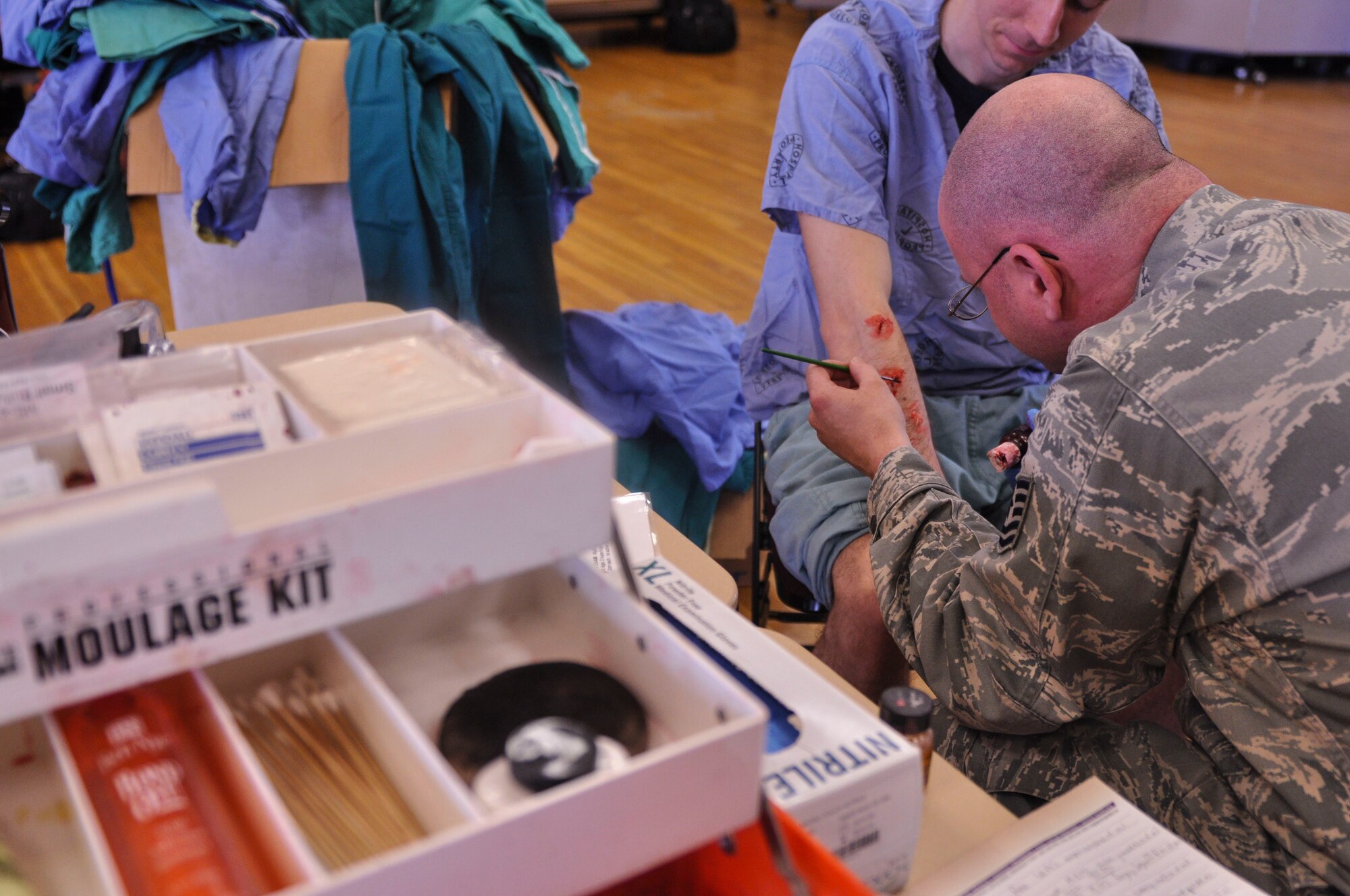 Team Little Rock Airmen prepare for a field training exercise by applying moulage to simulate casualties April 22, 2014, at Little Rock Air Force Base, Ark. The exercise was held at the University of Arkansas for Medical Sciences campus and was the largest of its type to date with more than 30 local, state and federal agencies involved. (U.S. Air Force photo by Senior Airman Regina Agoha)