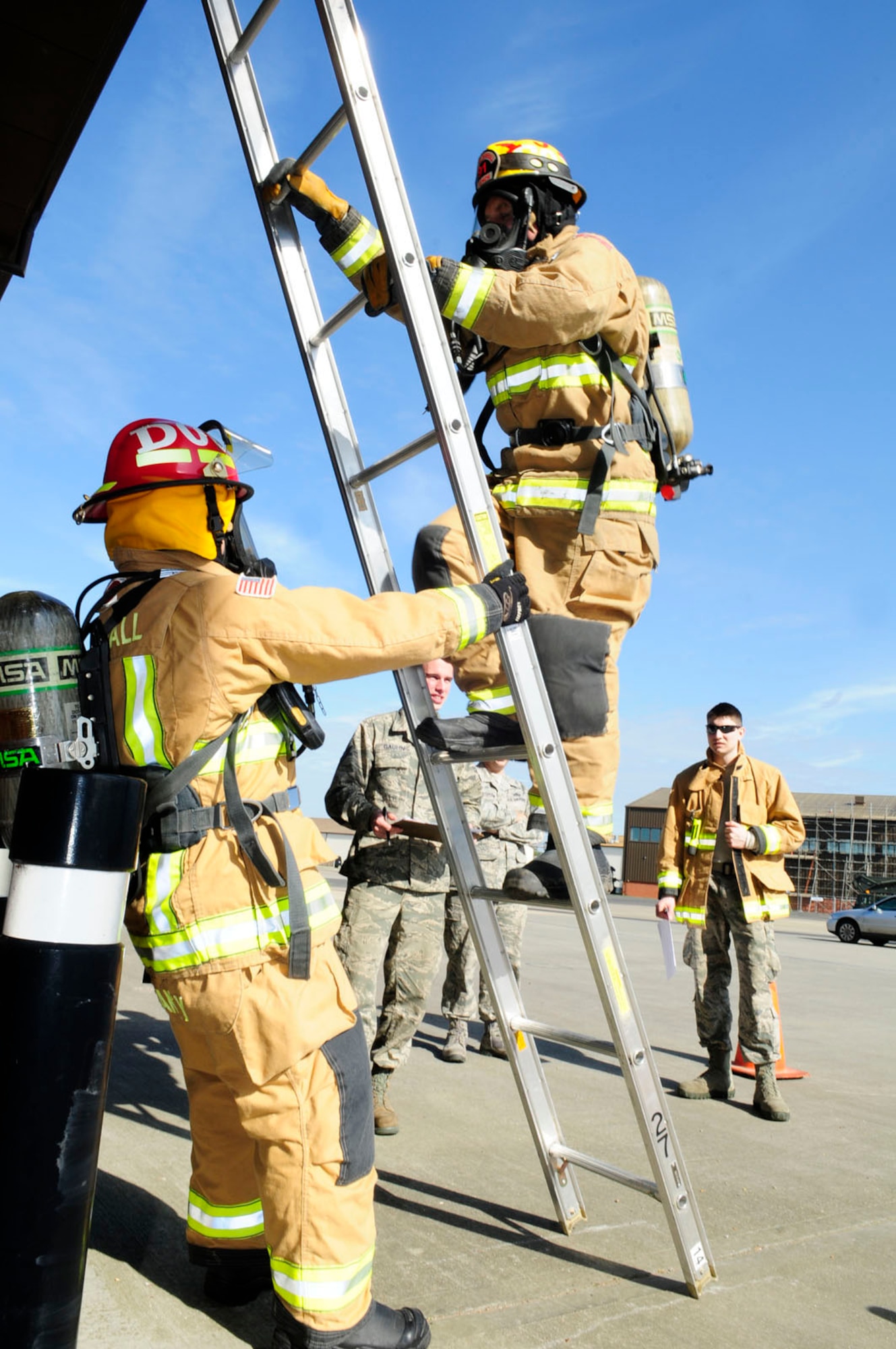 Watch Manager Adrian Delaney, left, 100th Civil Engineer Squadron Fire Department firefighter from Elmswell, Suffolk, holds a ladder as Firefighter Jason French, 100th CES Fire Department from Lakenheath, Suffolk, climbs during self-contained breathing apparatus training April 14, 2014, on RAF Mildenhall, England. Throughout April, firefighters here are undergoing annual training on respiratory protection and working in pairs through a course of six stations including a dummy drag, litter carry and hose hoist. The training is designed to determine the amount of air consumption by each firefighter, to work out how long a tank of oxygen would last them in a fire. (U.S. Air Force photo by Karen Abeyasekere/Released)