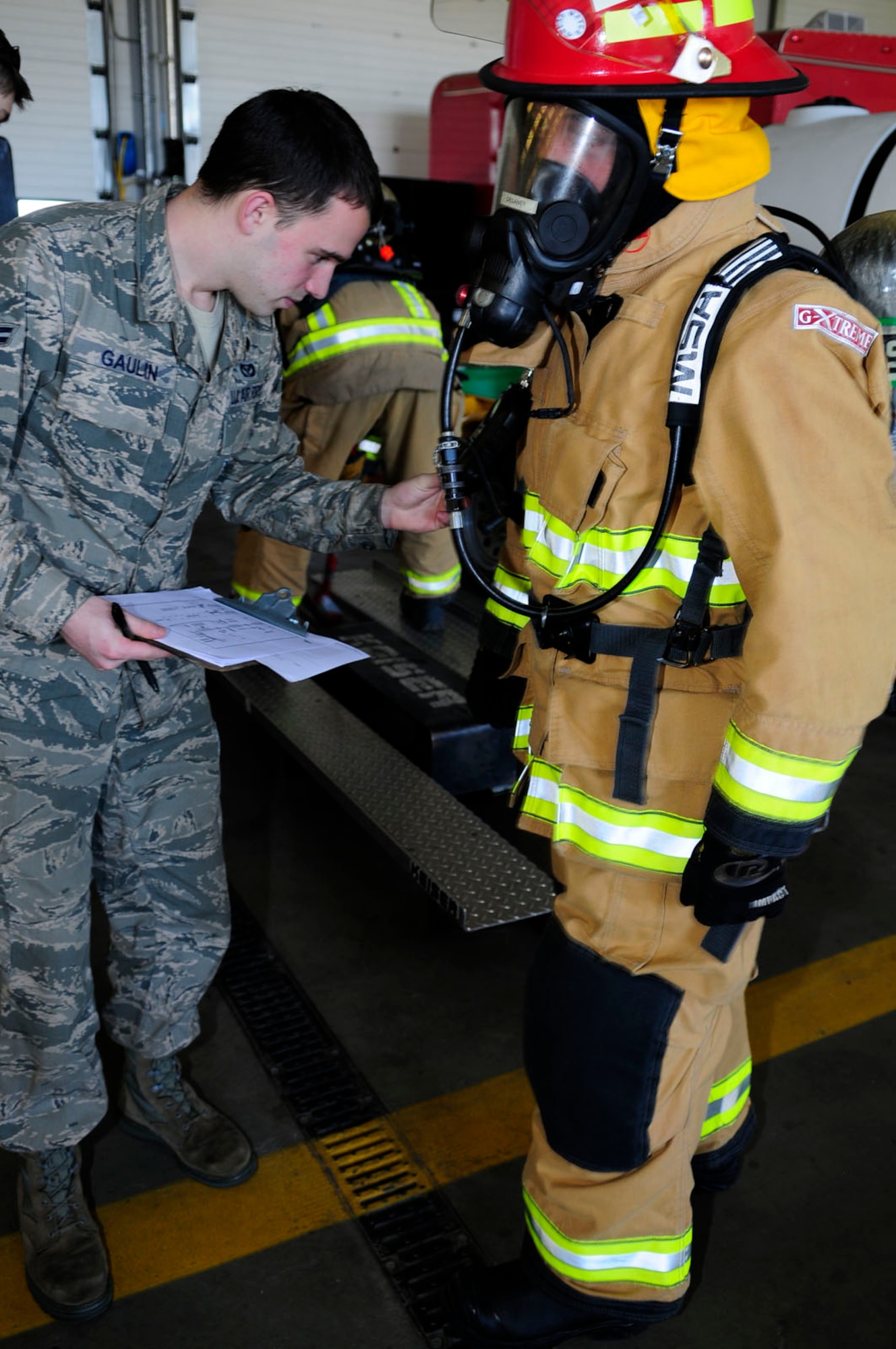 U.S. Air Force Airman 1st Class Christopher Gaulin, left, 100th Civil Engineer Squadron Fire Department firefighter from Hudson, Mass., checks the oxygen monitor on the self-contained breathing apparatus of Watch Manager Adrian Delaney, 100th CES Fire Department firefighter from Elmswell, Suffolk, April 14, 2014, during SCBA training on RAF Mildenhall, England. To comply with safety regulations, RAF Mildenhall's firefighters perform annual respiratory protection training, which ensures their SCBA equipment is constantly working and ready to go, and they know signs to look for when their oxygen is getting low. (U.S. Air Force photo by Karen Abeyasekere/Released)