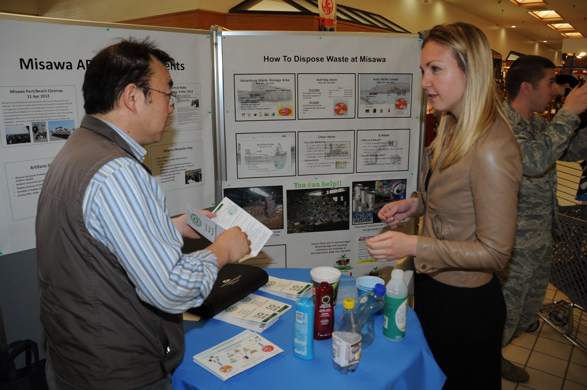 Hajime Sasaki, 35th Civil Engineer Squadron environmental engineer, informs Cari Schroeder, 35 CES resource efficiency manager, on the new recycling changes being implemented this summer on Misawa Air Base, Japan, April 22, 2014.  In the past, base residents only needed to rinse and contain their recyclables in a separate trash can for pickup, but times are changing. Be on the lookout for the recycling article next month. (U.S. Air Force photo/ Tech. Sgt. April Quintanilla)