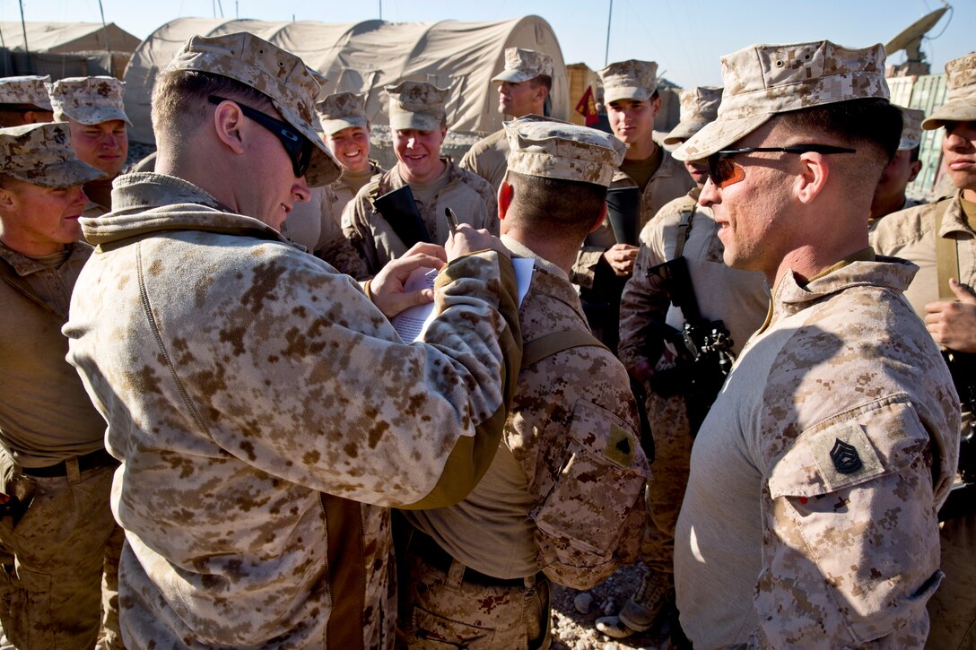 Dakota L. Meyer, a Medal of Honor recipient now serving as a U.S. Marine Corps sergeant in the reserves, autographs a copy of his citation during a visit to Forward Operating Base Shukvani in Afghanistan's Helmand province, Dec. 25, 2013. Meyer and Marine leaders traveled around Regional Command Southwest to visit troops for the holiday season.  