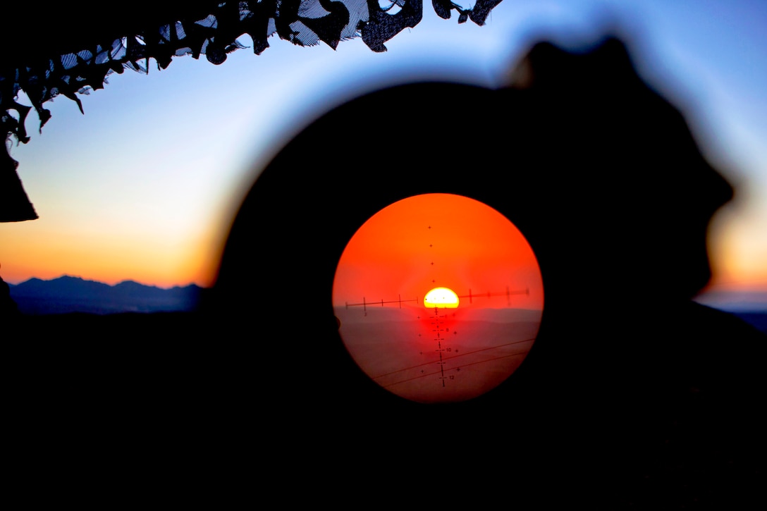 A U.S. Marine uses his weapon's optic lens to scan the mountaintops at sunset from a guard post on Observation Post Athens in Afghanistan's Helmand province, Nov. 28, 2013. The Marine is assigned to 3rd Battalion, 7th Marine Regiment, which provided security for personnel on Forward Operating Base Zeebrugge.  