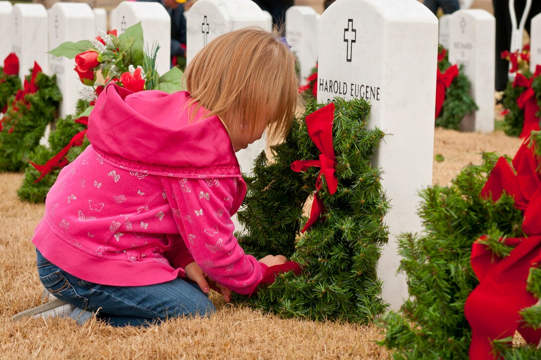 Carley Lawry, 5, places a wreath on a headstone at the Central Texas State Veterans Cemetery in Killeen, Texas, Nov. 30, 2013. More than 1,000 volunteers joined family members of the fallen to place more than 5,000 wreaths on the grave markers at the cemetery. The Friends of the Central Texas State Veterans Cemetery organized the event.  