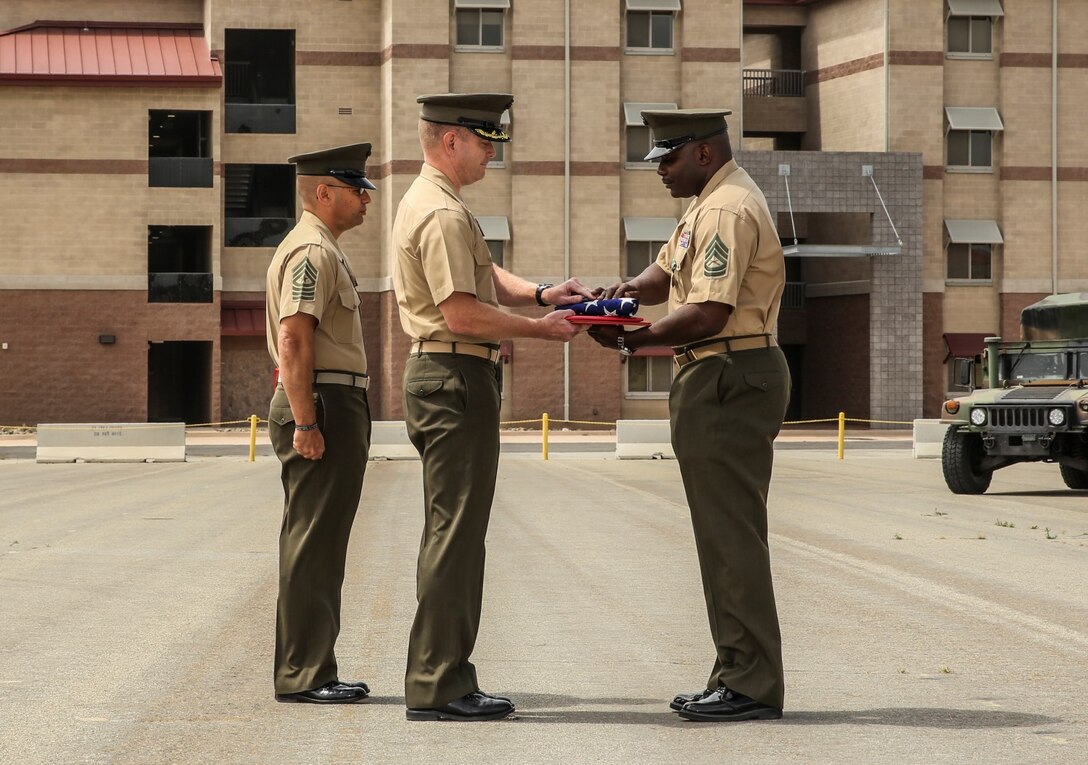 Lieutenant Col. John R. O’Neal, middle, commanding officer, 15th Marine Expeditionary Unit, presents an American flag to Gunnery Sgt. Treneil L. Smith, logistics chief, 15th Marine Expeditionary Unit, during his retirement ceremony aboard Camp Pendleton, Calif., April 25, 2014. Smith, 40, is from Detroit. (U.S. Marine Corps photo by Cpl. Emmanuel Ramos/Released)