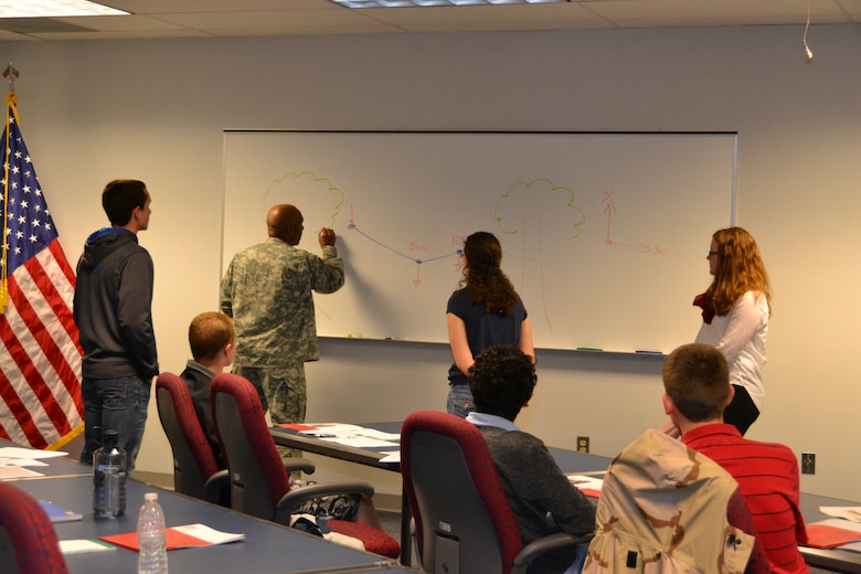 Col. Vincent Quarles, Middle East District commander, works through a sample engineering problem with students during Day with an Engineer.