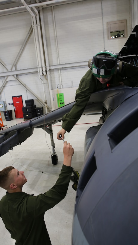 Lance Cpl. Bryce Wexell hands Lance Cpl. Erika Minnix a socket wrench with an extension while repairing an AV-8B Harrier at Marine Attack Training Squadron 203 aboard Marine Corps Air Station Cherry Point, N.C., April 21, 2014. Wexell and Minnix are maintenance Marines with the squadron who are charged with repairing, maintaining and inspecting aircraft. VMAT-203 trains student pilots to fly the Harrier.