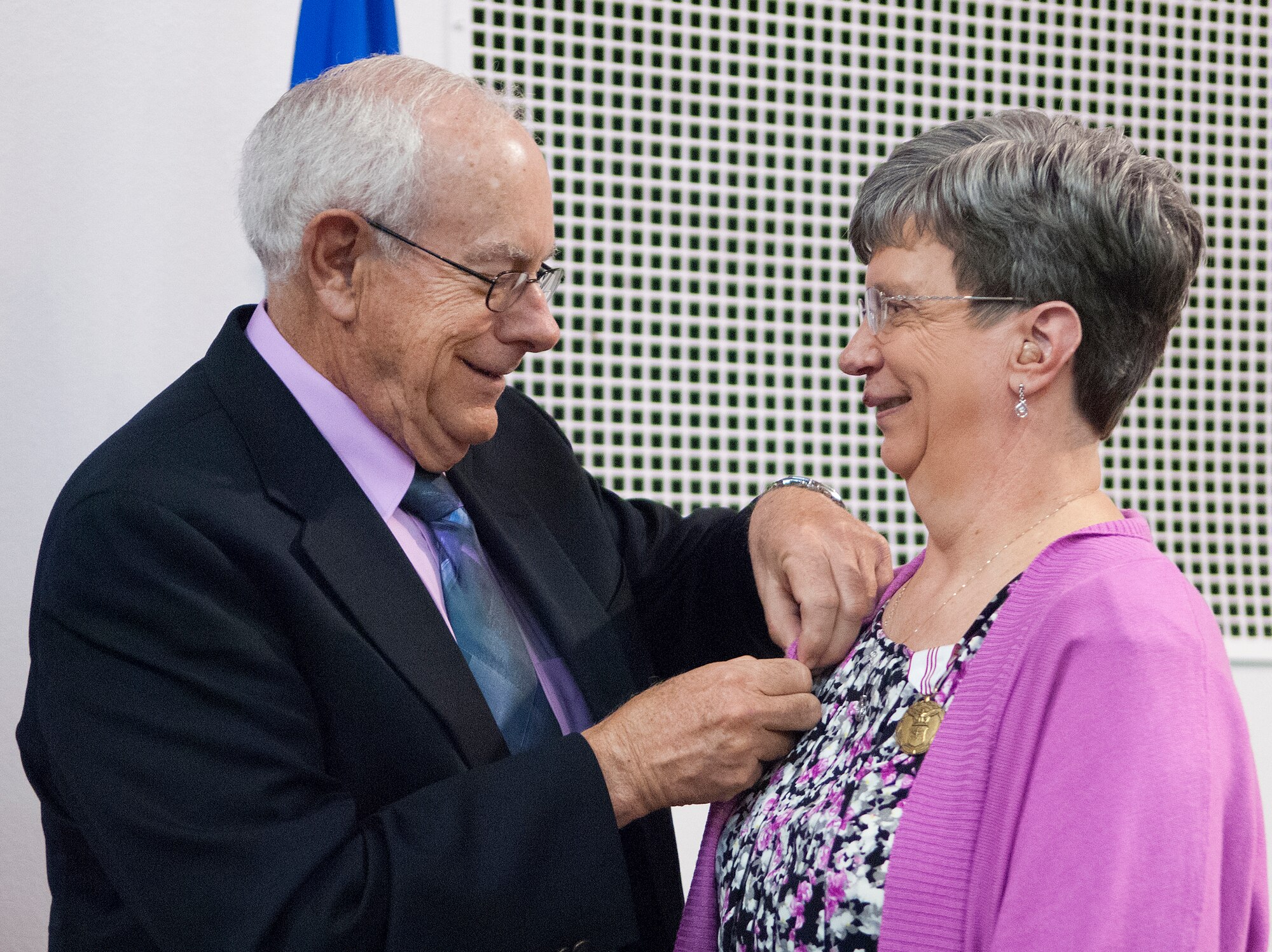 Pat Connors pins the retirement pin on the lapel of his wife, Nila Connors, during a ceremony in Fall Hall April 30, 2014, marking her retirement after 30 years of government service. Connors was also awarded the Outstanding Civilian Career Service Award for her lengthy service — most notably her 12 years as secretary to the commander of the 90th Missile Wing, and its predecessor the 90th Space Wing, on F.E. Warren Air Force Base, Wyo. (U.S. Air Force photo by R.J. Oriez)