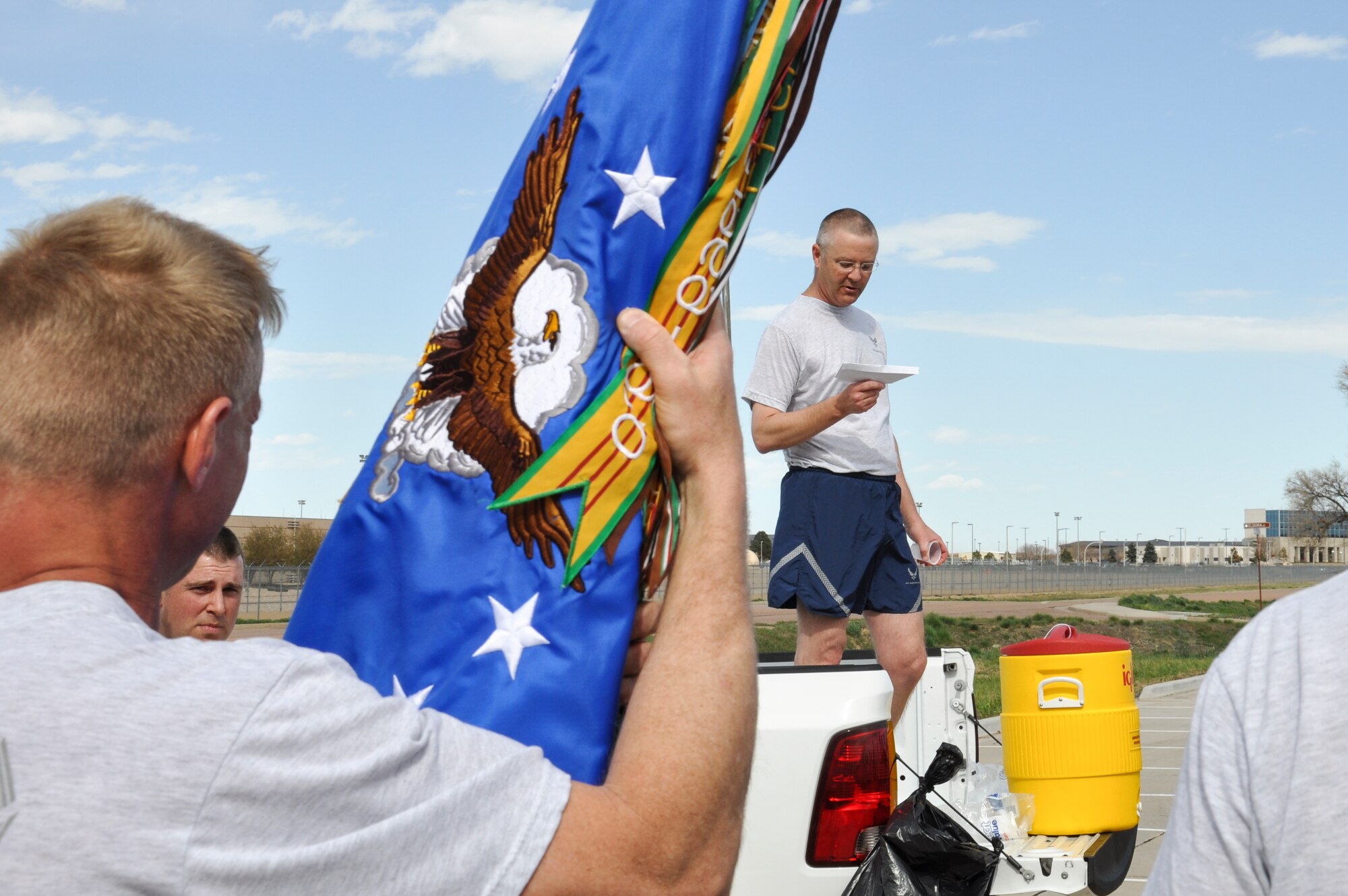 Col. Michael Kindt, 460th Medical Group commander, reads base history to Team Buckley members during a quick stop of the 2.5-mile WarFit formation run April 25, 2014, at Buckley Air Force Base, Colo. The workout included segments on base history and stops for anaerobic exercises. (U.S. Air Force photo by Staff Sgt. Nicholas Rau/Released)