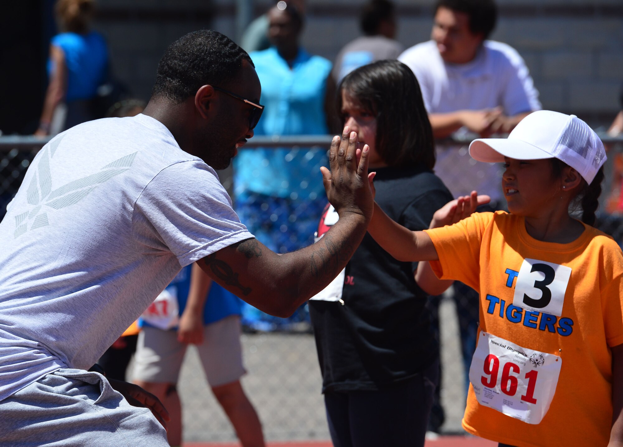 Staff Sgt. Brandon Cox, 57th Maintenance Operations Squadron precision guided missiles crew chief, high-fives a girl before she competes in the 50-meter race at the Nevada Special Olympics at Cheyenne High School in Las Vegas May 1, 2014. More than 240 Airmen from Nellis and Creech Air Force Bases volunteered their time during the two day event to help unite the community and set an example through fitness and sports play.