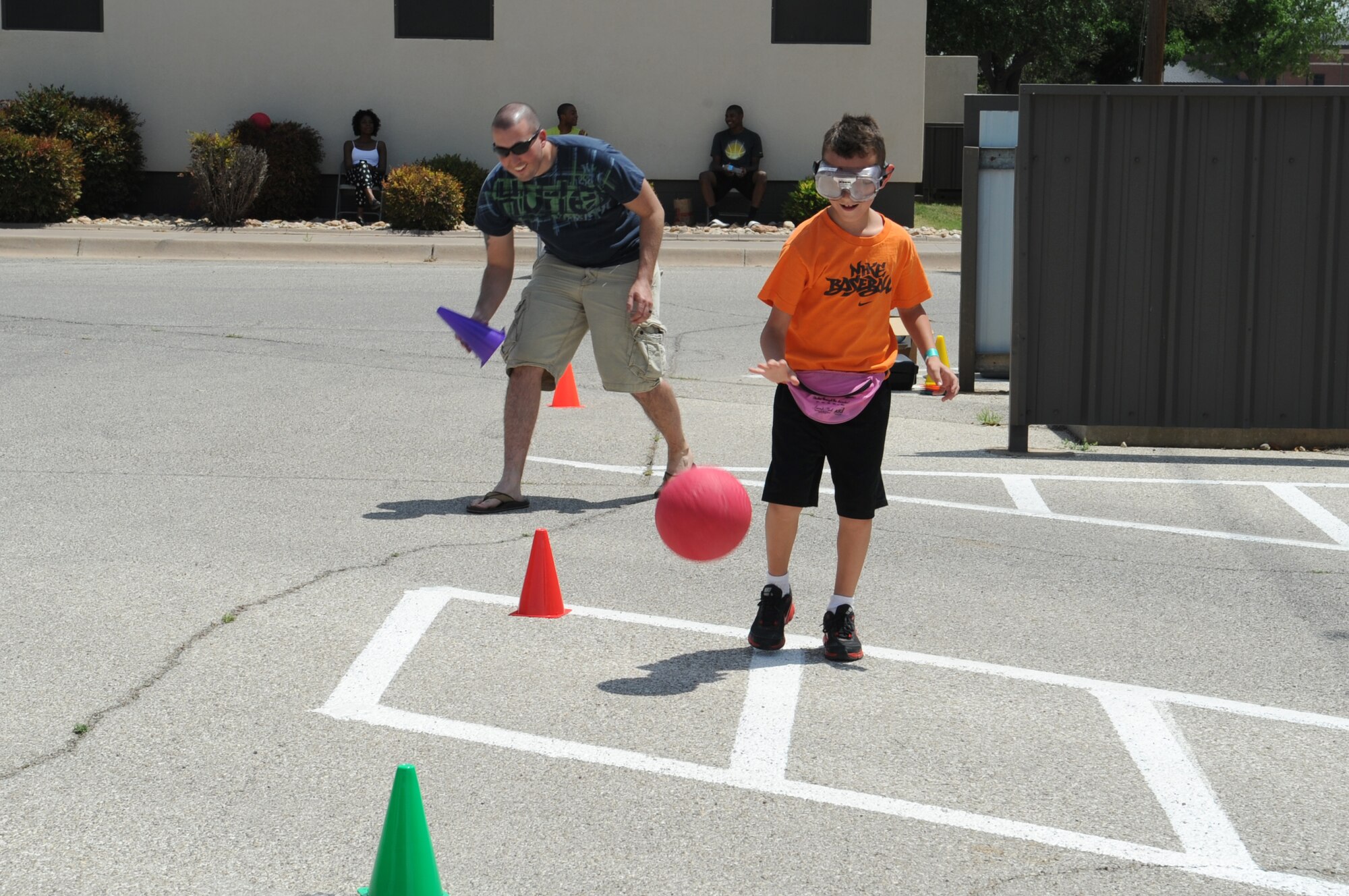 GOODFELLOW AIR FORCE BASE, Texas -- Senior Airman Charles A. Metts III, 17th Medical Operations Squadron Alcohol and Drug Abuse Prevention and Treatment technician, picks up cones as a Goodfellow youth dribbles the ball during the 4th Annual Sexual Assault and Response Coordinator Challenge here April 26. Participants dribbled the ball around the cones while wearing glasses that distort vision. (U.S. Air Force photo/ Staff Sgt. Laura R. McFarlane)