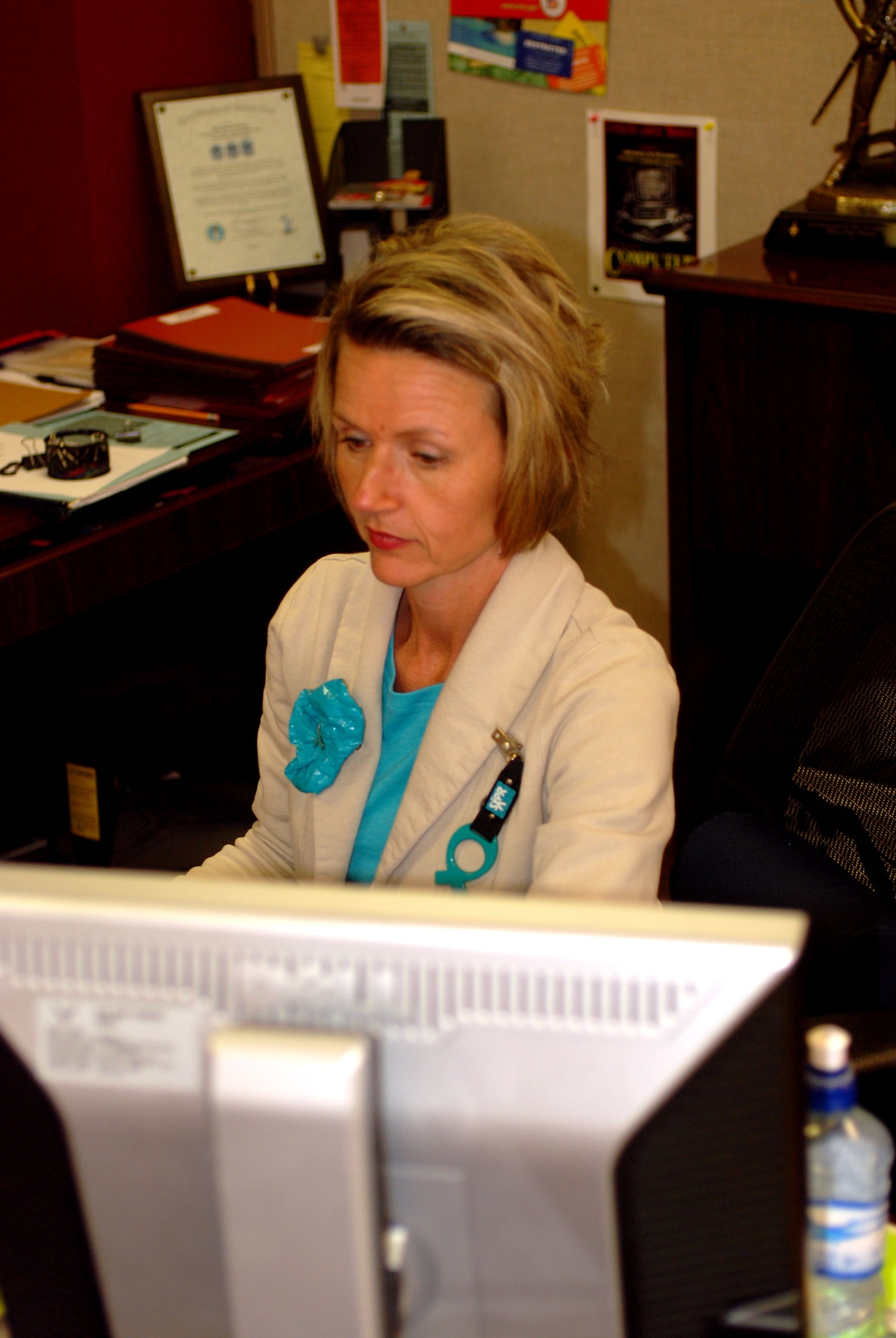 Tech. Sgt. Tina Pressy sits at her desk while wearing her teal and ribbon. The 181st Intelligence Wing has a no tolerance policy on sexual assault.
