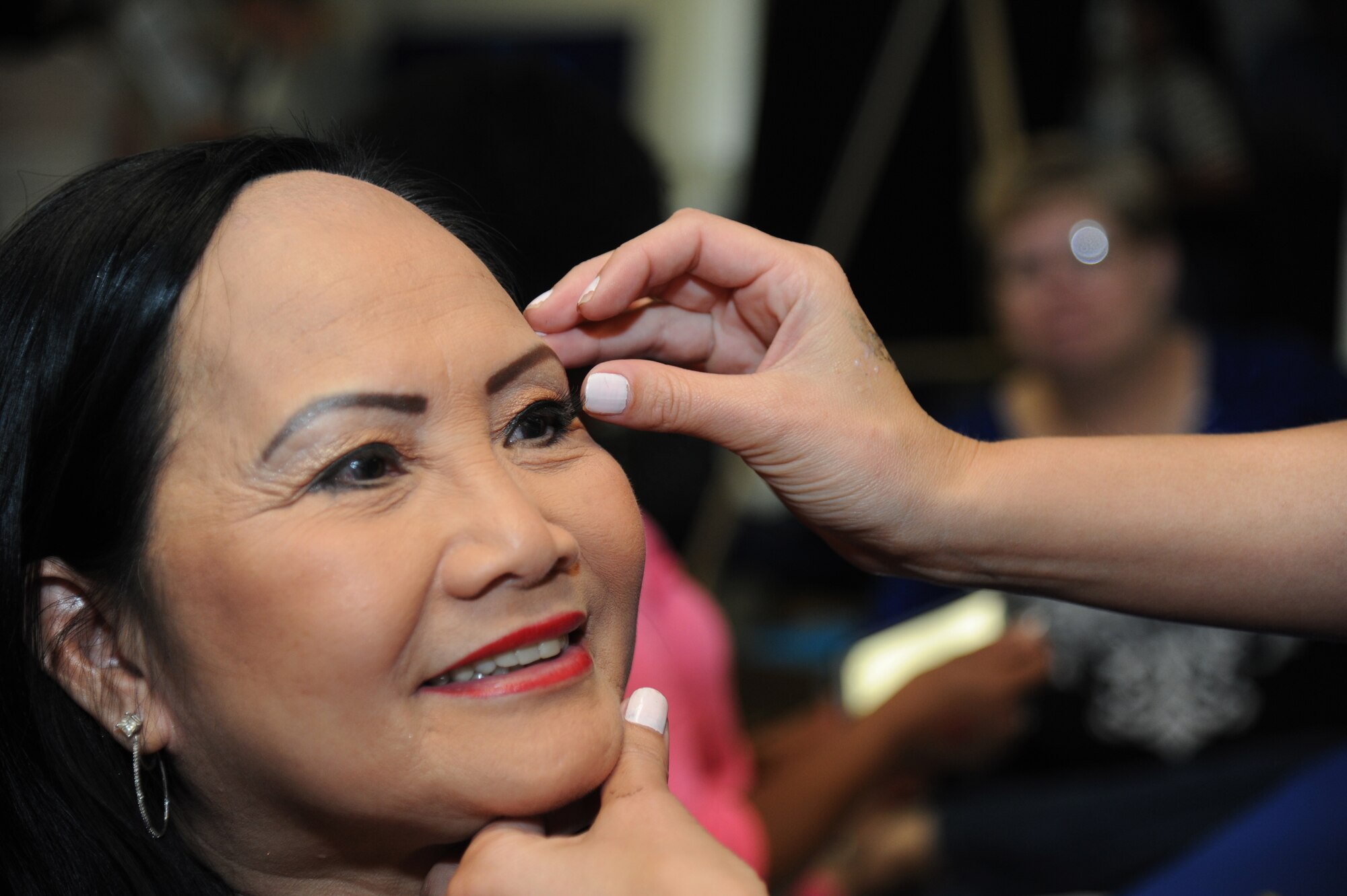 The spouse of retired Navy Chief Carl Kozuma holds her eye lid steady as she has artificial eye lashes put on during Pamper Me Day for military spouses May 1, 2014, at the Sablich Center, Keesler Air Force Base, Miss.  Keesler’s Airman& Family Readiness Center has hosted the event for the past 10 years, offering spouses free manicures, hair styling, makeup and massages.  (U.S. Air Force photo by Kemberly Groue)