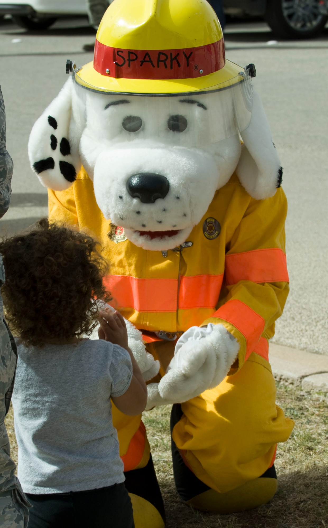Sparky the firedog greets Khloe Santos, daughter of Staff Sgt. Hannah Santos, after the Month of the Military Child Parade April 29, 2014, at Dyess Air Force Base, Texas. There are approximately 2 million children with one or more parents serving in the armed forces. Since 1986, April has been designated as the Month of the Military Child to celebrate the contributions military children make. (U.S. Air Force photo by Airman 1st Class Kylsee Wisseman/Released)