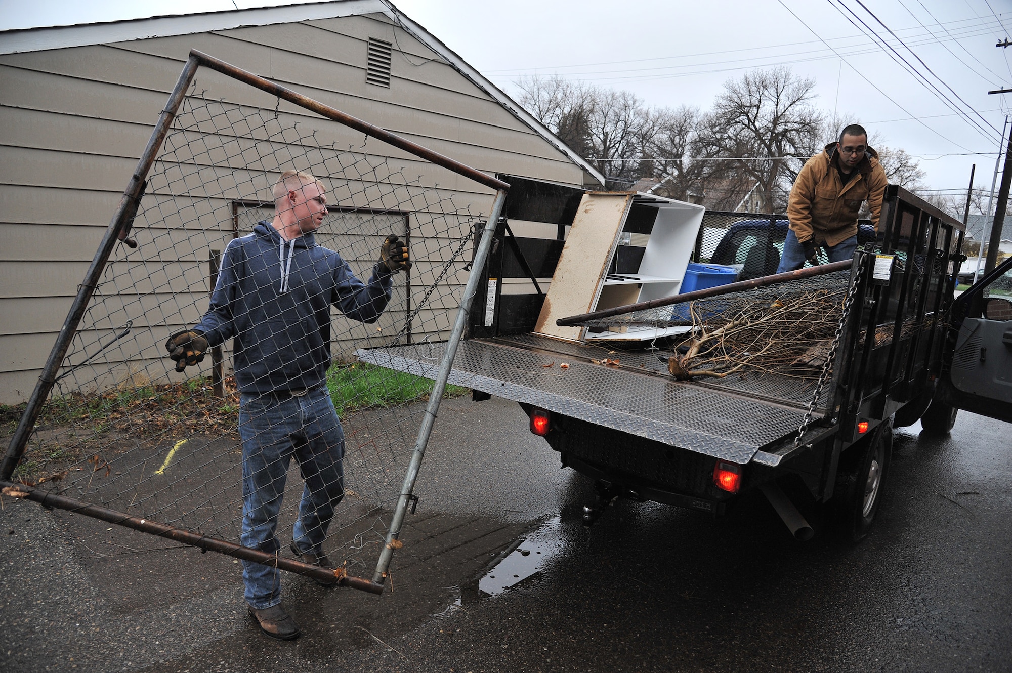 From left to right, Airman 1st Class Tucker Morgan and Senior Airman Myster Duran, both from the 341st Civil Engineer Squadron, load discarded items onto a truck April 26 during MApril cleanup in Great Falls. (U.S. Air Force photo / John Turner)