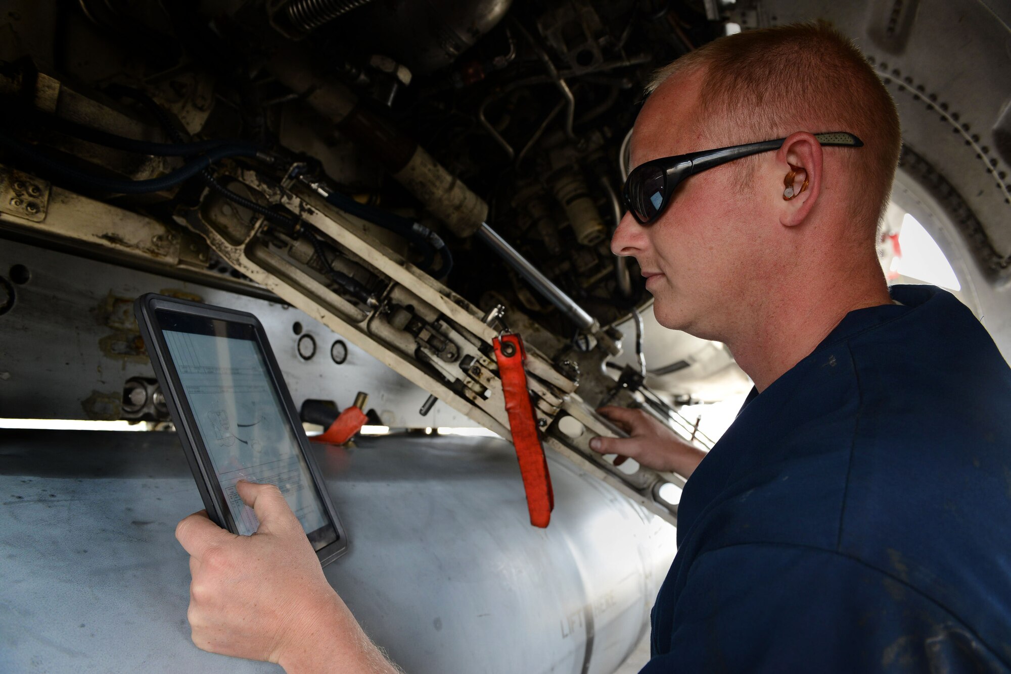 U.S. Air Force Senior Airman Matthew Leke, 20th Aircraft Maintenance Squadron, 55th Aircraft Maintenance Unit tactical aircraft maintainer, examines the inside of an F-16CJ Fighting Falcon at Shaw Air Force Base, S.C., April 29, 2014.  Leke was using an iPad while testing its usability in place of a technical order manual during post-flight inspections. (U.S. Air Force photo by Airman 1st Class Jensen Stidham/Released)