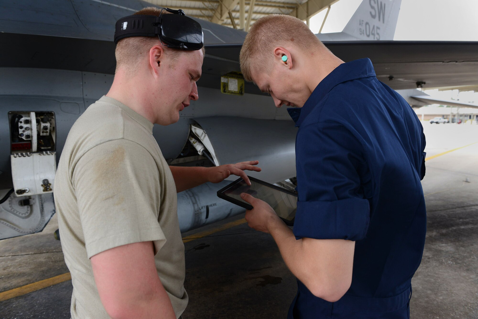Airman 1st Class Dominic Vaughn explains to Airman Eric Bain, both 20th Aircraft Maintenance Squadron, 55th Aircraft Maintenance Unit tactical aircraft maintainers, how to navigate an iPad version of a technical order manual at Shaw Air Force Base, S.C.,  April 29, 2014. The 55th AMU was selected to test the new iPad to determine its usability and reliability on the flight line. (U.S. Air Force photo by Airman 1st Class Jensen Stidham/Released)