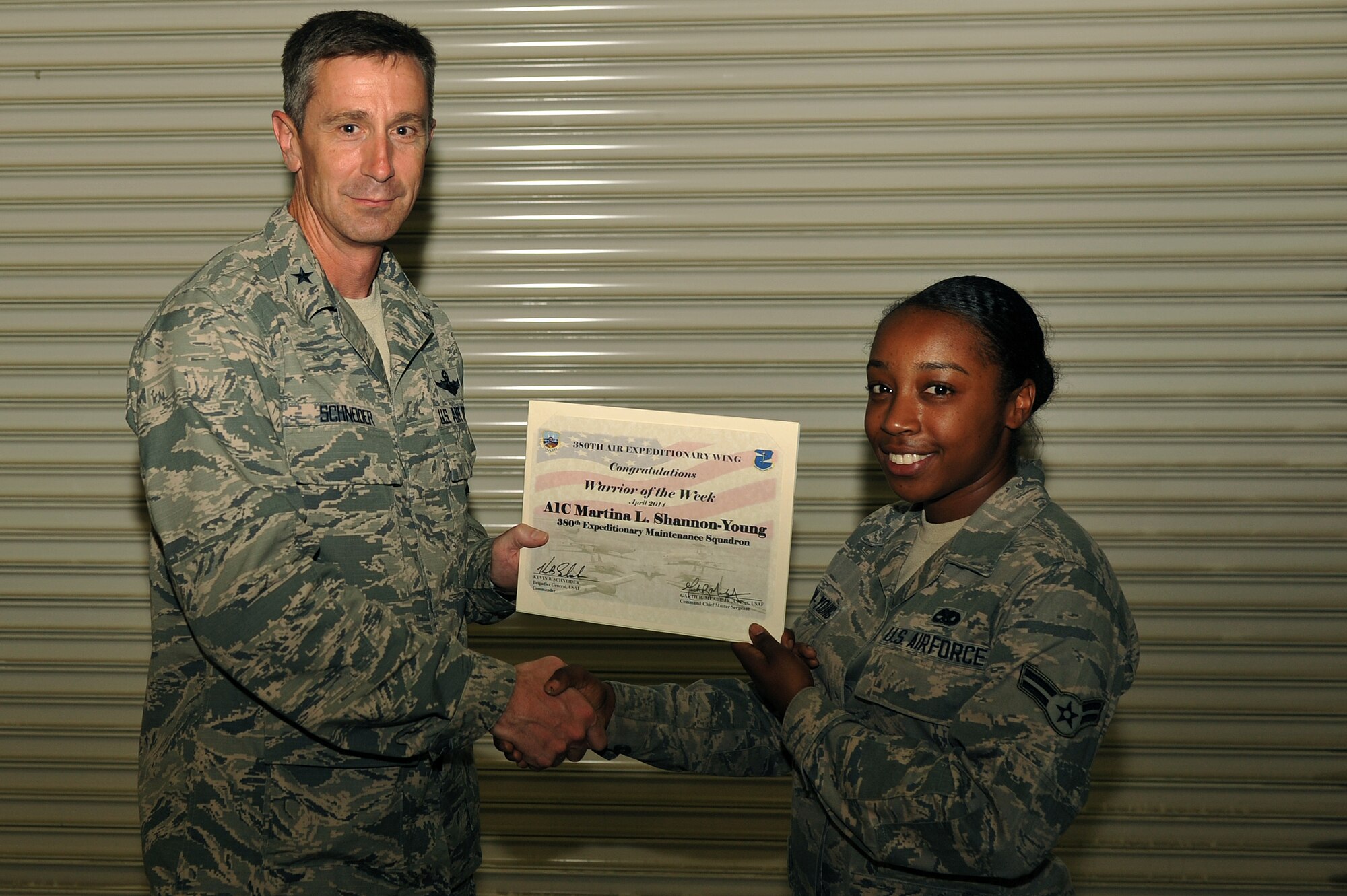 Air Force Brig. Gen. Kevin Schneider, 380th Air Expeditionary Wing commander, presents Airman 1st Class Martina Shannon-Young , a 380th Expeditionary Aircraft Maintenance Squadron  aerospace ground equipment journeyman, with a warrior of the week certificate at an undisclosed location in Southwest Asia, April 29, 2014. Shannon-Young is a native of Floral Park, NY. and is deployed from RAF Lakenheath, England. Her hobbies include fitness, reading and pursuing education. (U.S. Air Force photo by Tech. Sgt. Russ Scalf/Released)