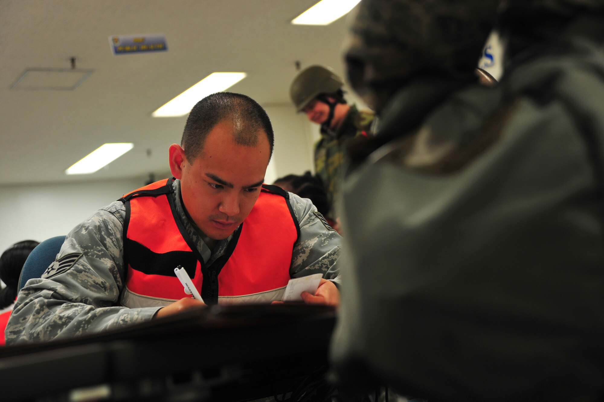 U.S. Air Force Staff Sgt. Ahdel Manapat, 35th Force Support Squadron force management supervisor, checks mobility documents of “deploying” members at a personnel deployment function line as part of Phase I of an Operational Readiness Exercise at Misawa Air Base, Japan, May 1, 2014. All documents and training records required of personnel deploying are checked and verified at PDF lines. (U.S. Air Force photo/Senior Airman Jose L. Hernandez-Domitilo)