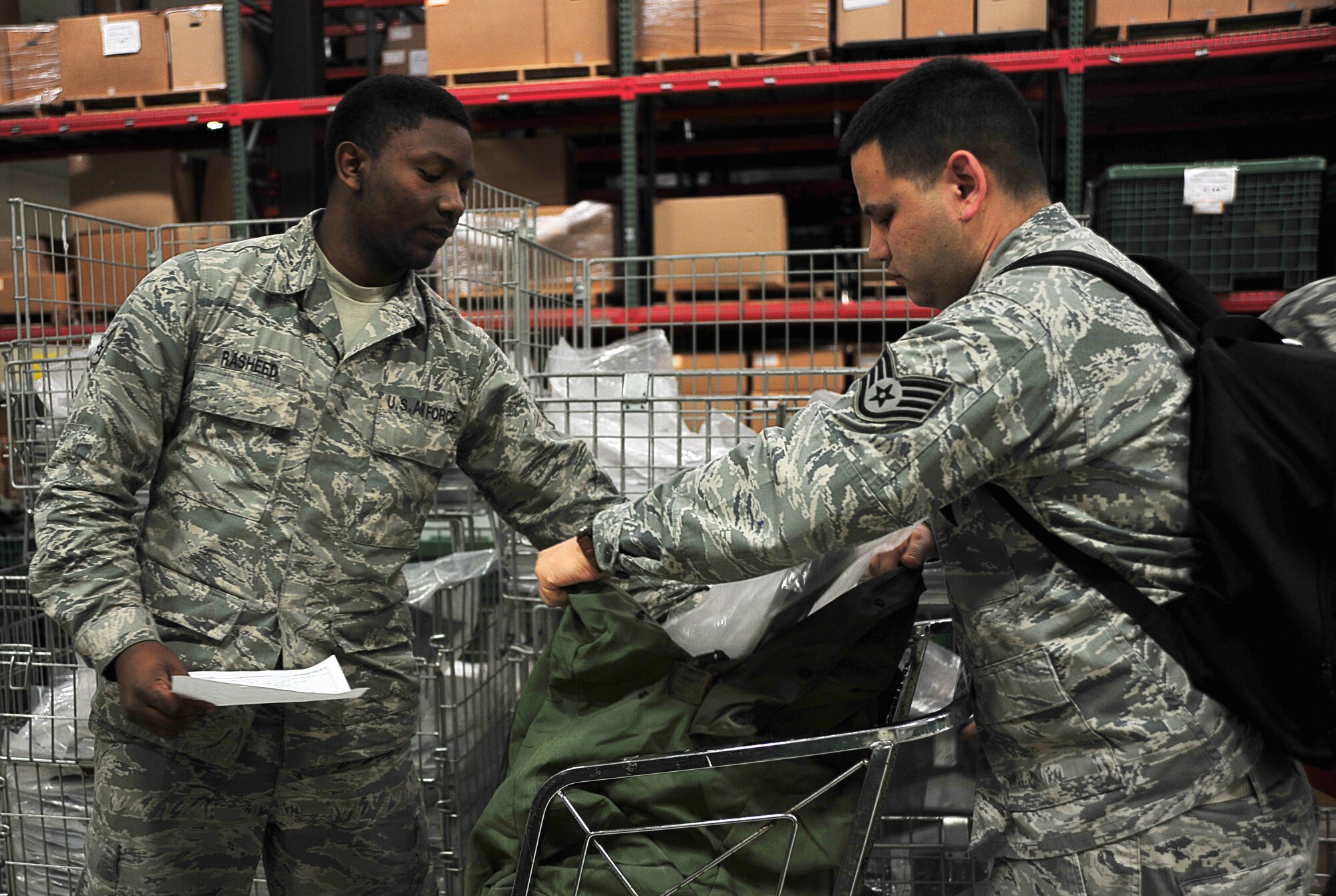 U.S. Air Force Airman 1st Class Elijah Rasheed, 35th Logistics Readiness Squadron material management journeyman, provides Staff Sgt. Johnathan Leddy, 14th Fighter Squadron aviation resource management, with deployment gear at Misawa Air Base, Japan, May 1, 2014. Supply Airmen provide field gear necessary for deployments with items like gas masks, vest, helmets, sleeping bags, and individual first-aid kits, among other items. (U.S. Air Force photo/Senior Airman Jose L. Hernandez-Domitilo)