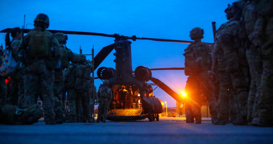 Army Rangers stand on a flightline while pilots prepare a CH-47 Chinook helicopter for takeoff on Fort Knox, Ky., April 21, 2014. The pilots are assigned to the 160th Special Operations Aviation Regiment.