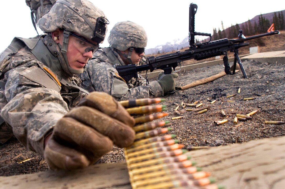 Army Pvt. Bryan Iratcabal, foreground, reaches for a linked belt of 5.56mm ammunition while Army Pfc. Victor Serrano waits to fire his M249 squad automatic weapon during training on Joint Base Elmendorf-Richardson, Alaska, April 23, 2014. Iratcabal and Serrano are assigned to the 23rd Engineer Company, 6th Engineer Battalion Combat, Airborne, 2nd Engineer Brigade, Alaska.