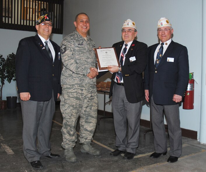Eugene Kachena, American Legion Department of North Dakota commander, presents Master Sgt. Angus Adolpho with the 2013 North Dakota American Legion Firefighter of the Year Award during a special presentation ceremony at Grand Forks Air Force Base, N.D. on April 30, 2014. Adolpho is the assistant chief of standards and evaluations from the Grand Forks Air Force Base Fire Department. Pictured at opposite ends are (from left to right) Robert Greene, the commander of the Treumann-Webb-Phelps Post #6 of Grand Forks and Rodney Kadlec, American Legion East Region vice commander North Dakota. (U.S. Air Force photo/Staff Sgt. Luis Loza Gutierrez) 