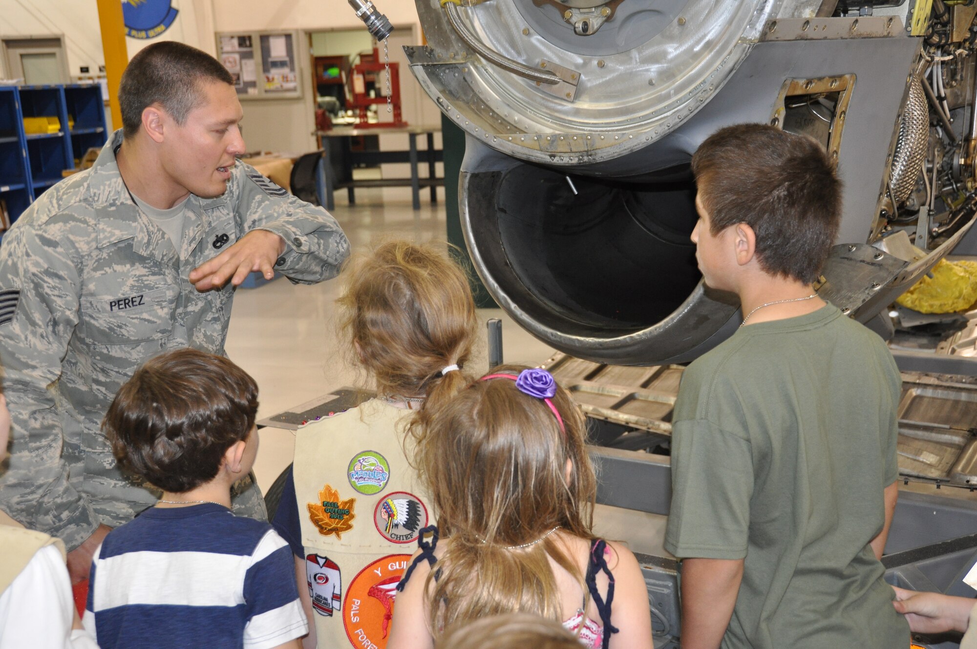 POPE FIELD, N.C. - Tech. Sgt. Emmanuel Perez, a propulsion craftsman with the 440th Maintenance Squadron explains the inner workings of a jet engine to members of a Y Princess troop from Raleigh, North Carolina as well as reserve family members at the 2014 Passport to Adventure held here, May 3.  