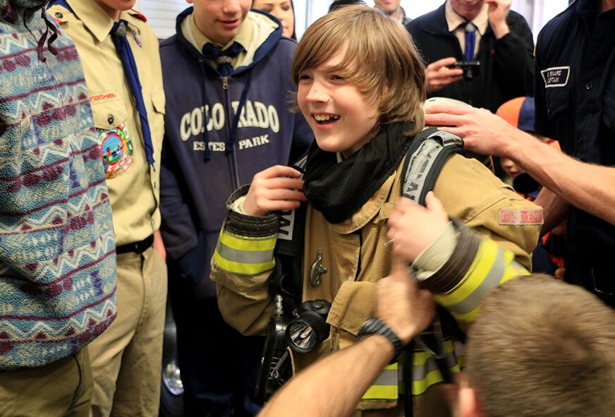 Colin Rocks, Boy Scout with Troop 171 out of Seattle, tries on fire fighter gear at a Joint Base Lewis-McChord fire department during a base tour May 3. The firefighters taught the scouts aspects of their job and let them try on gear, climb inside the trucks and see the equipment. (U.S. Air Force Reserve photo by Senior Airman Madelyn McCullough)