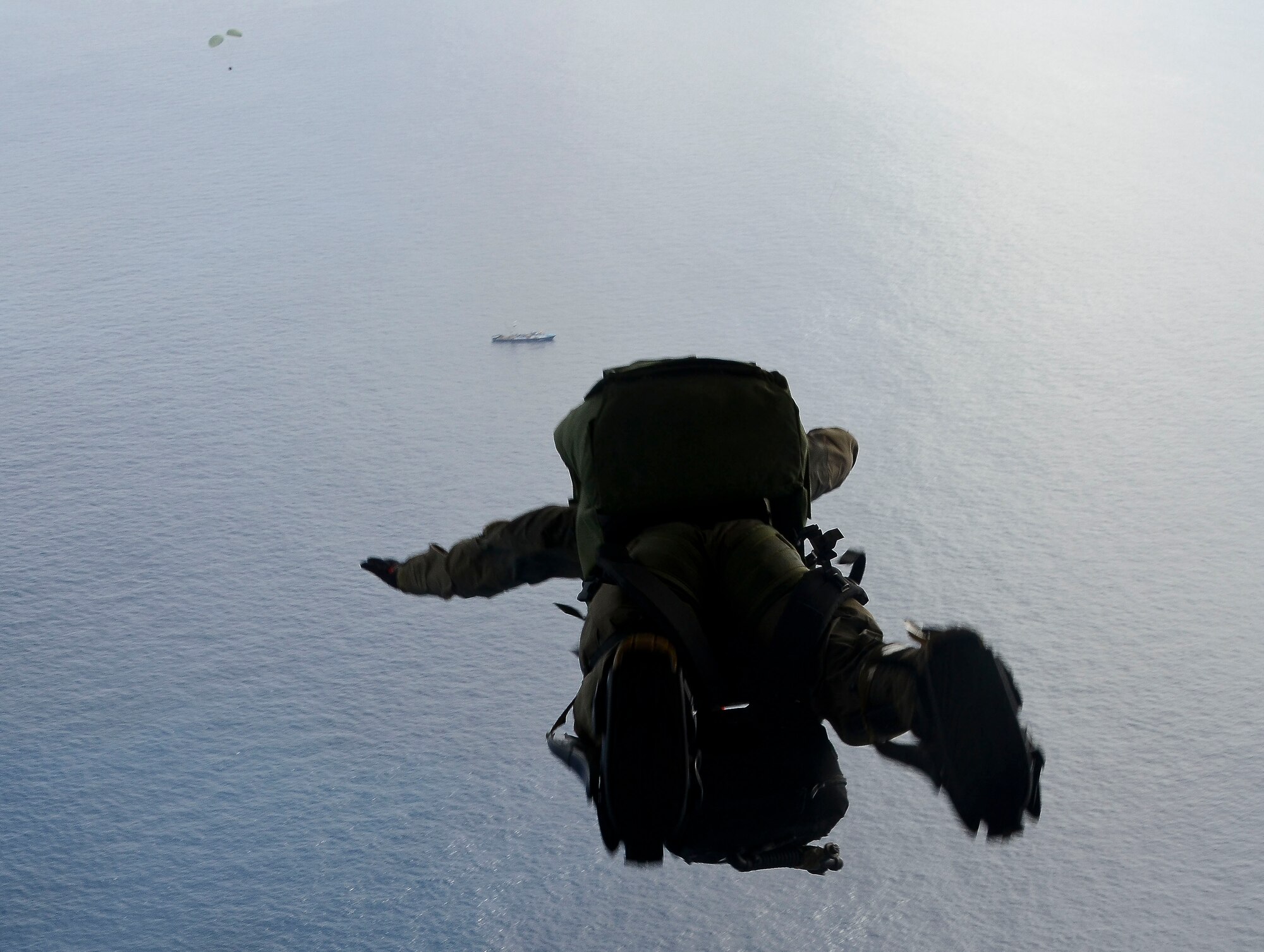 A U.S. Air Force pararescue Airman from the 48th Rescue Squadron parachutes into the Pacific Ocean to aid to two critically injured sailors aboard a Venezuelan fishing boat May 3, 2014. The Airmen flew in two HC-130J Combat King II aircraft and three HH-60 Pavehawk helicopters for nearly 11 hours, and then parachuted into the ocean 1,100 nautical miles from the Mexican coast with two inflatable zodiac boats and medical equipment to deliver lifesaving care. (U.S. Air Force photo by Staff Sgt. Adam Grant/Released) 
