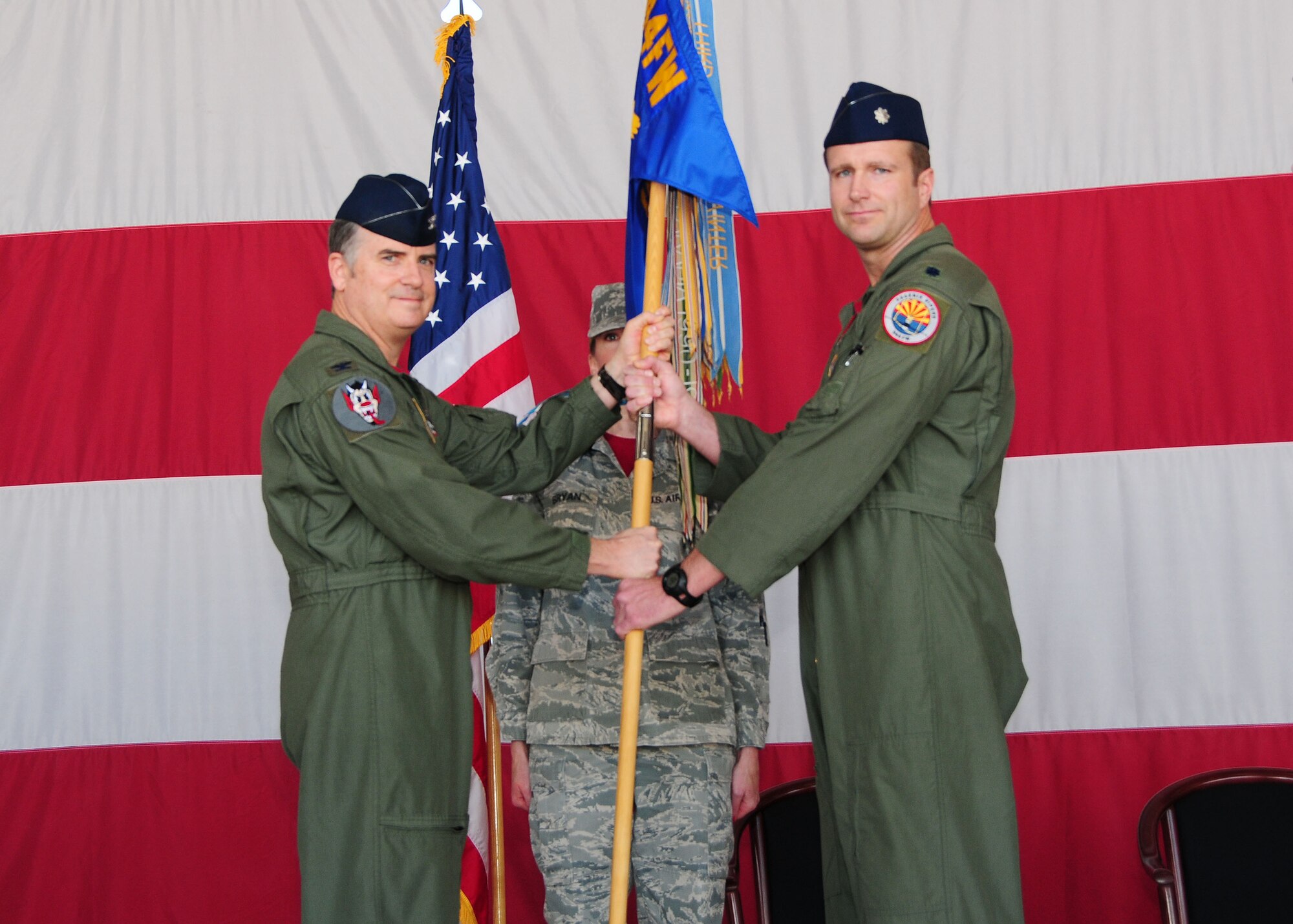Col. Gregory Jones, 944th Operations Group commander, passes the guidon to Lt. Col. Korey Amundson May 2 as he assumes command of the 69th Fighter Squadron. Lt. Col. Gerald Brown relinquished command during the change-of-command ceremony. (U.S. Air Force photo/Tech Sgt. Louis Vega Jr.)
