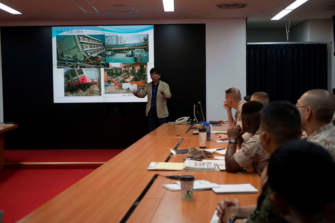 Tetsuo Takashima, standing, addresses Marine Corps planners and executors of disaster relief operations, as well as Japan Self-Defense Force liaison officers, May 1 on Camp Courtney to enhance disaster relief operations. Takashima is an author and natural and human disaster expert. The U.S. service members are with various units assigned to III Marine Expeditionary Force. 