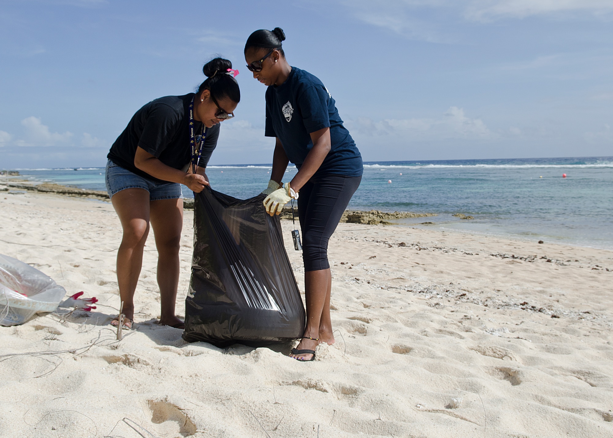Navy Petty Officer 1st Class Petagaye Blair, Naval Airborne Weapons Maintenance Unit 1 leading petty officer, and Navy Petty Officer 2nd Class Deardre Bebeau, Supply logistics specialist, bag a tire for recycling during the 2nd Annual Earth Day Tarague Beach Cleanup on Andersen Air Force Base, Guam.  The base holds official beach cleanups twice each year, for Earth Day and then again in September for the annual Guam International Coastal Cleanup, though Boys and Girl Scouts and other civic organizations perform beach cleanups throughout the year.(U.S. Air Force photo by Senior Airman Katrina Brisbin/Released)