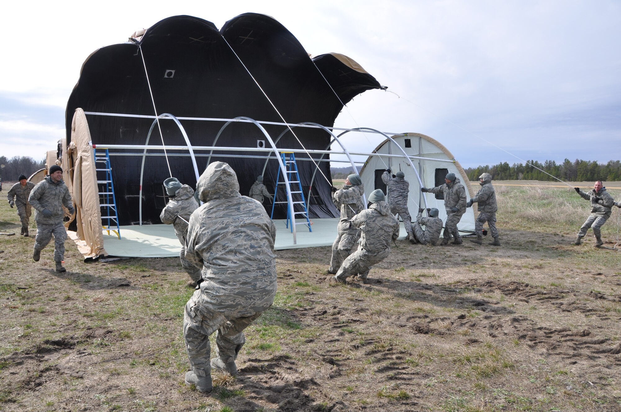 Reservists with the 433rd Civil Engineer Squadron fight the extreme windy conditions at Fort McCoy, Wis. April 28 to finish building a tent in support of Exercise Patriot Warrior 2014.  These Alamo Wing Airmen are used to sunny, warm conditions at Joint Base San Antonio- Lackland, but adjusted quickly to cold, wet and windy weather. “The first few days here were rough,” said Capt. David Shaw, 433rd Operations Flight Commander. “This event of turning the tent into a temporary sail resulted in laughter, boosted morale and reset the mood.”  