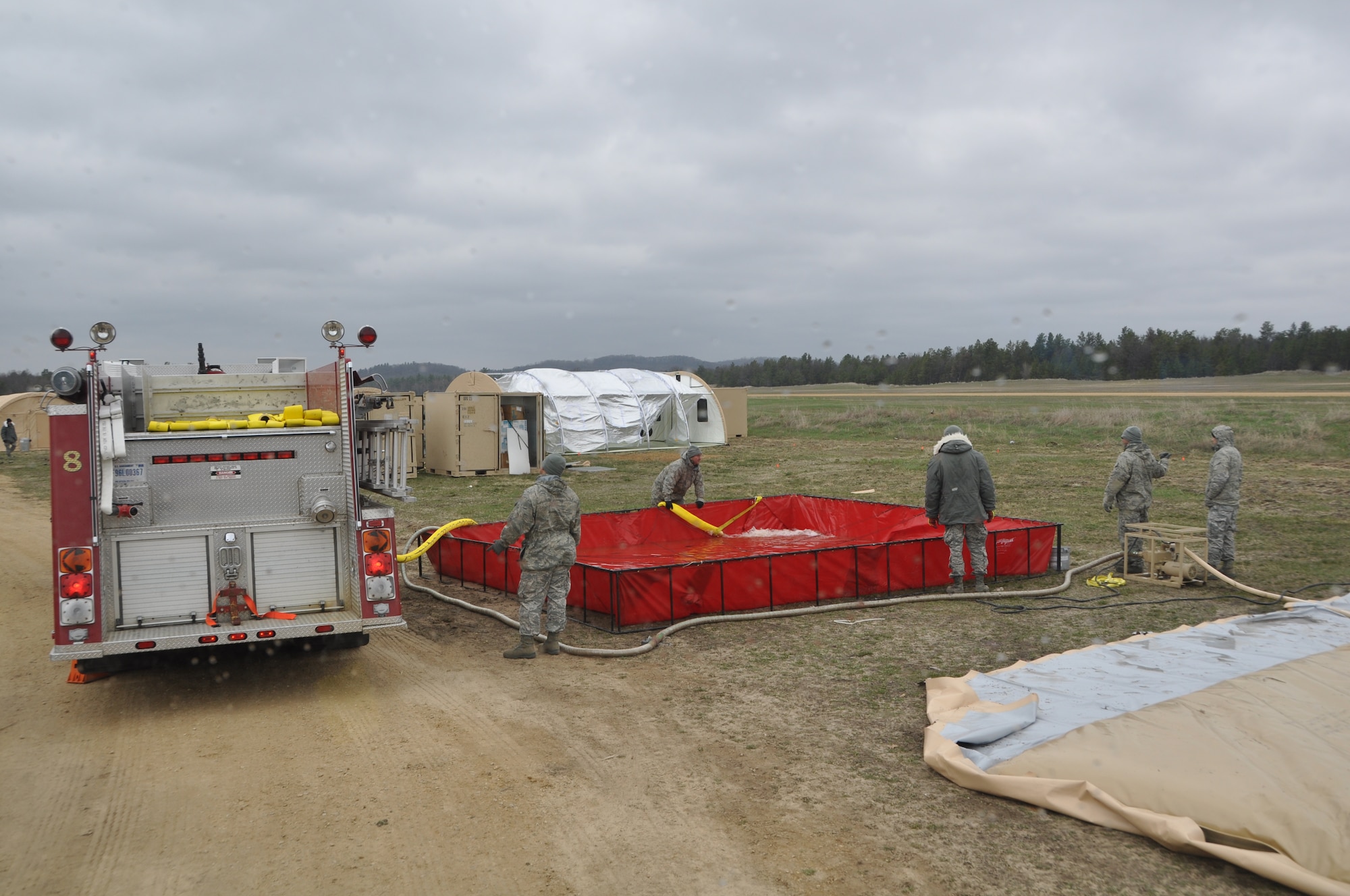 Firefighters with the 433rd Civil Engineer Squadron, empty water extracted from a nearby lake in Fort McCoy, Wis., into a bladder April 27. The water will be filtered through a Reserve Osmosis Water Purification Unit and used for showering and drinking for the duration of Exercise Patriot Warrior 2014. Fire fighters aided in the bed down and sustainment of bare base operations in preparation for the exercise that trains medical personnel to move injured war fighters out of a war zone for further medical care. (U.S. Air Force photo by 1st Lt. Denise Haeussler)