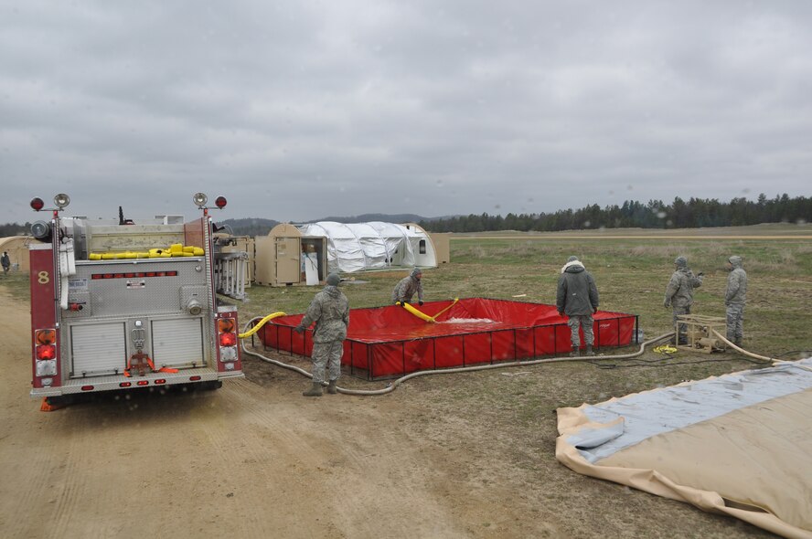 Firefighters with the 433rd Civil Engineer Squadron, empty water extracted from a nearby lake in Fort McCoy, Wis., into a bladder April 27. The water will be filtered through a Reserve Osmosis Water Purification Unit and used for showering and drinking for the duration of Exercise Patriot Warrior 2014. Fire fighters aided in the bed down and sustainment of bare base operations in preparation for the exercise that trains medical personnel to move injured war fighters out of a war zone for further medical care. (U.S. Air Force photo by 1st Lt. Denise Haeussler)