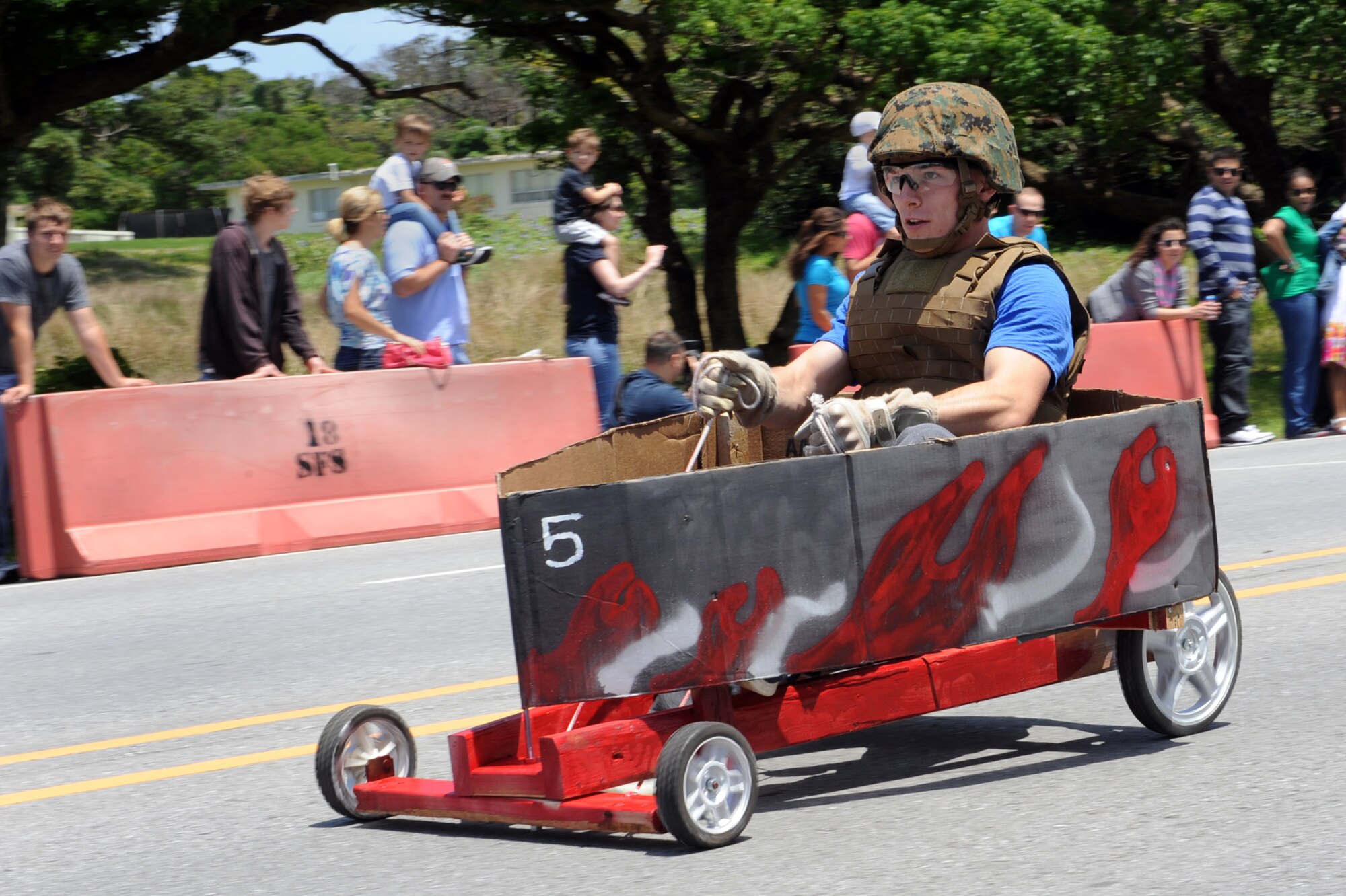 U.S. Marine Corps Lance Cpl. Alex Palmer, 3rd Marine Expeditionary Force Marine Air Ground Task Force planning specialist, steers his entry into the Red Cross Derby Day competition, “The G5,” down Douglas Avenue on Kadena Air Base, Japan, April 26, 2014. More than 25 active duty and civilian teams competed, generating more than $5,000 for Red Cross disaster relief services. (U.S. Air Force photo by Airman 1st Class Zade C. Vadnais)